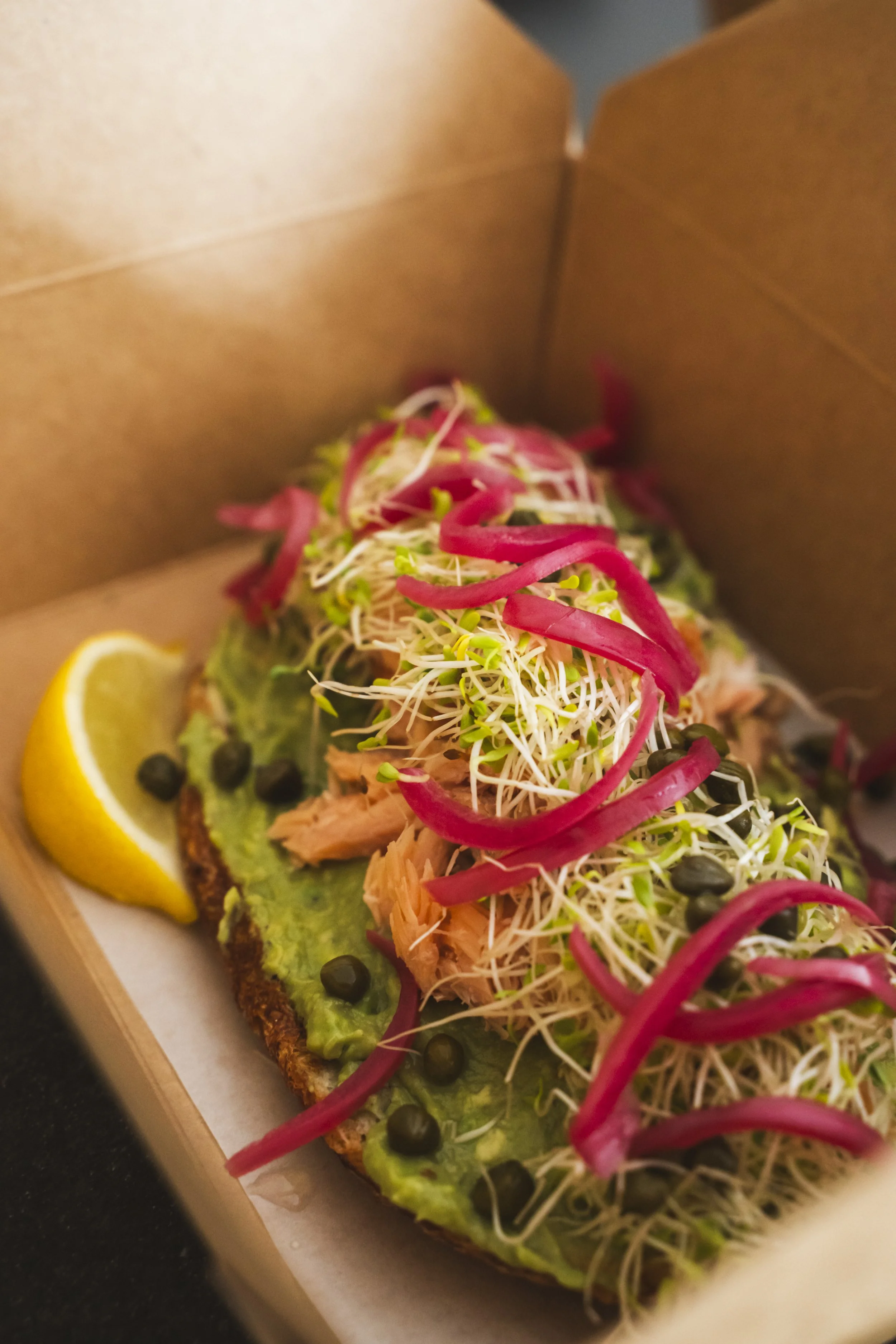 Smoked salmon toast piled high with capers, pickled red onions, and fresh sprouts at Eddy’s Marketplace – Grab & Go, a neighborhood coffee shop and gourmet market in downtown Aspen.