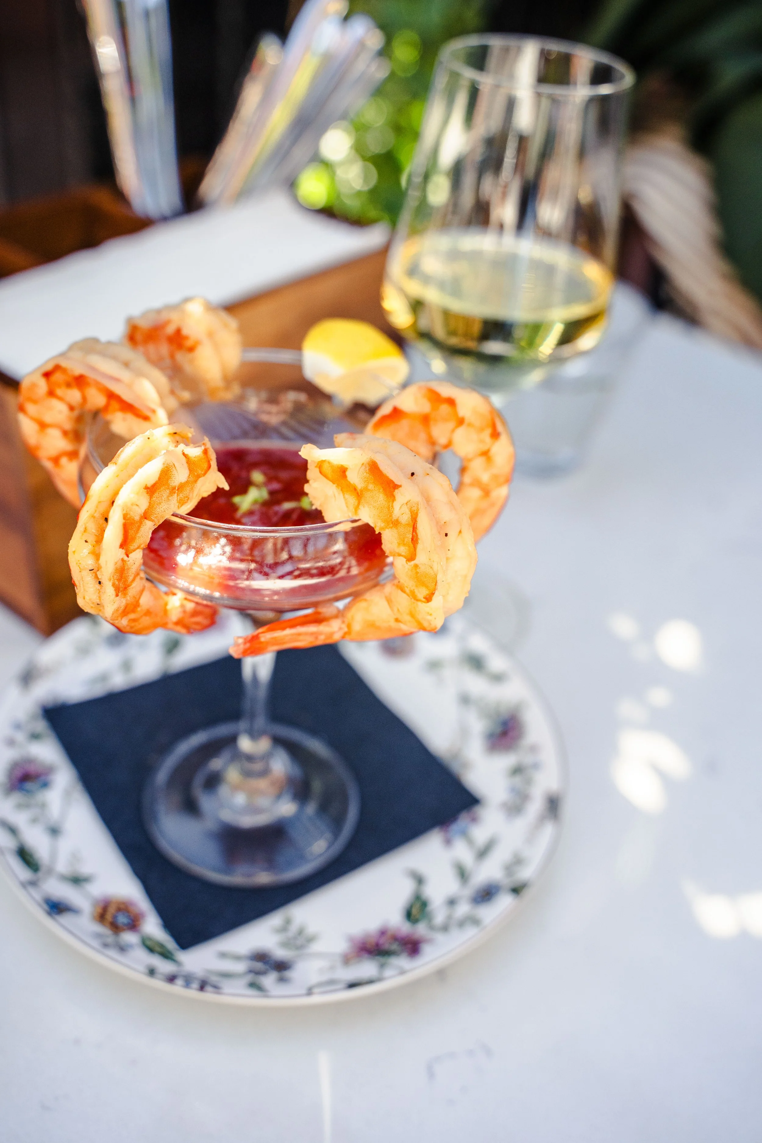 Shrimp cocktail served outdoors with a chilled glass of white wine for casual patio dining at Eddy’s Kitchen in downtown Aspen.