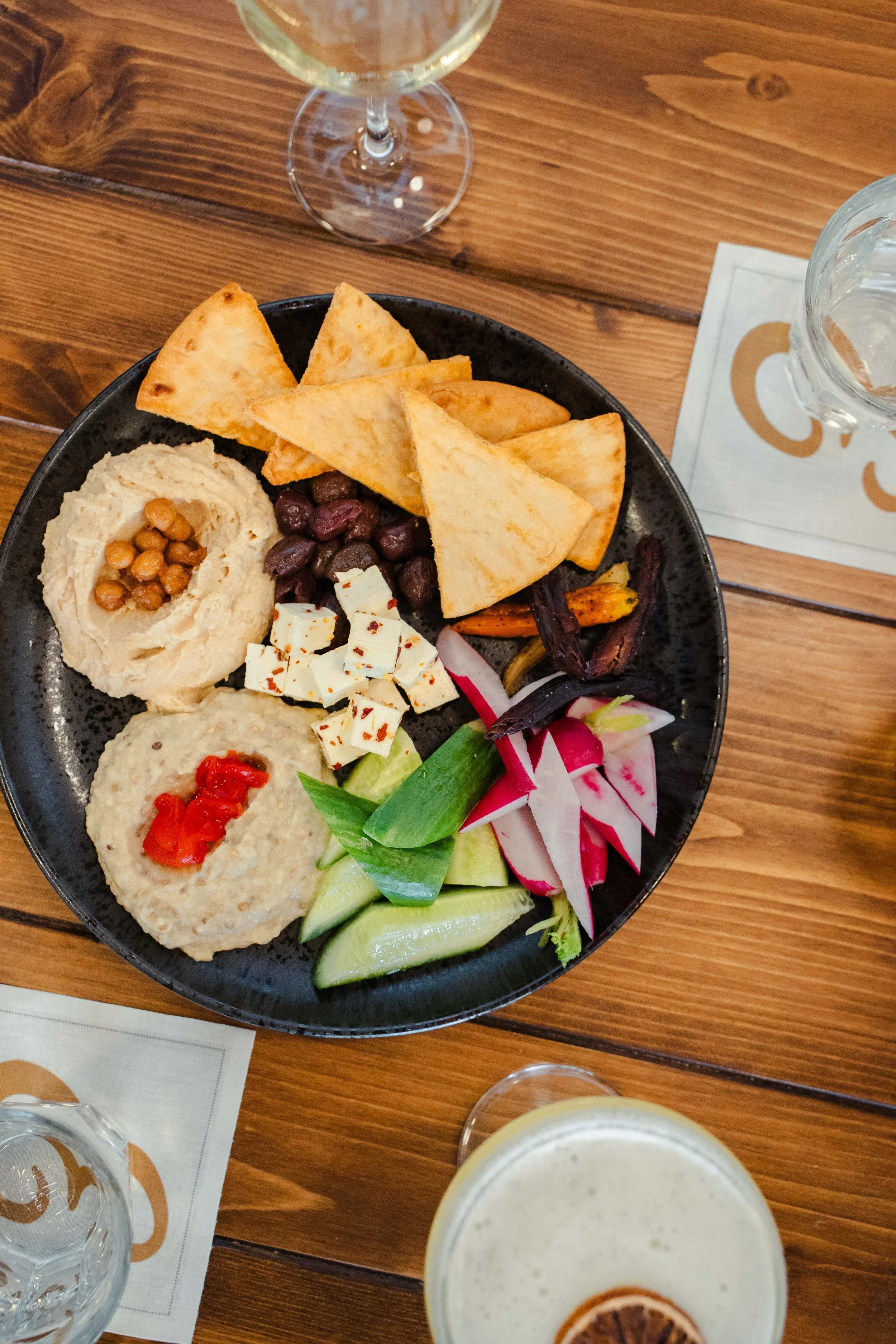 Mezze platter with homemade hummus, baba ganoush, warm pita, fresh vegetable crudités, and cocktails at Eddy’s Kitchen in downtown Aspen.