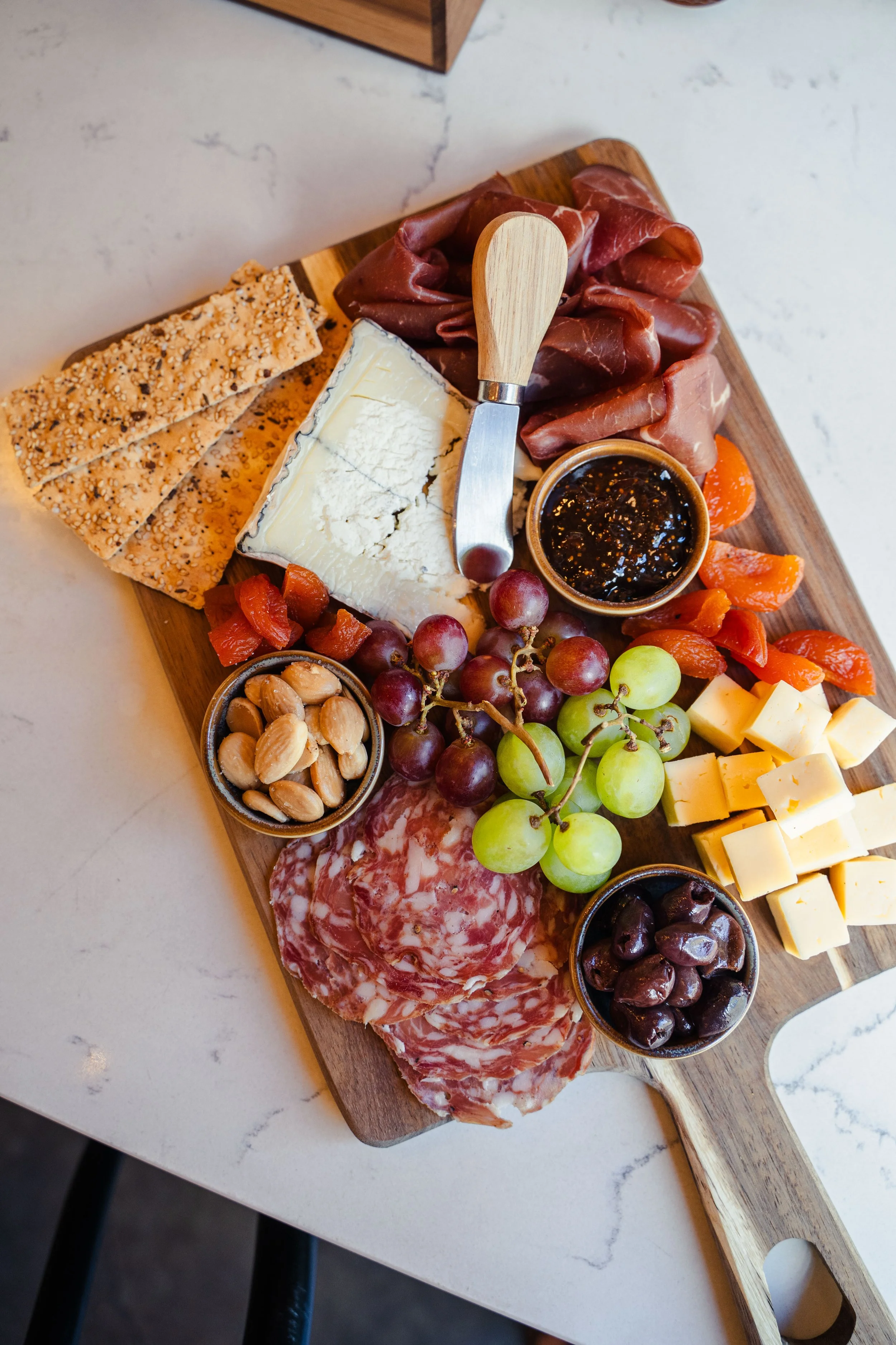 Gourmet charcuterie board with artisan cheeses, cured meats, fresh fruit, crackers, nuts, and fig jam at Eddy’s Kitchen in downtown Aspen.