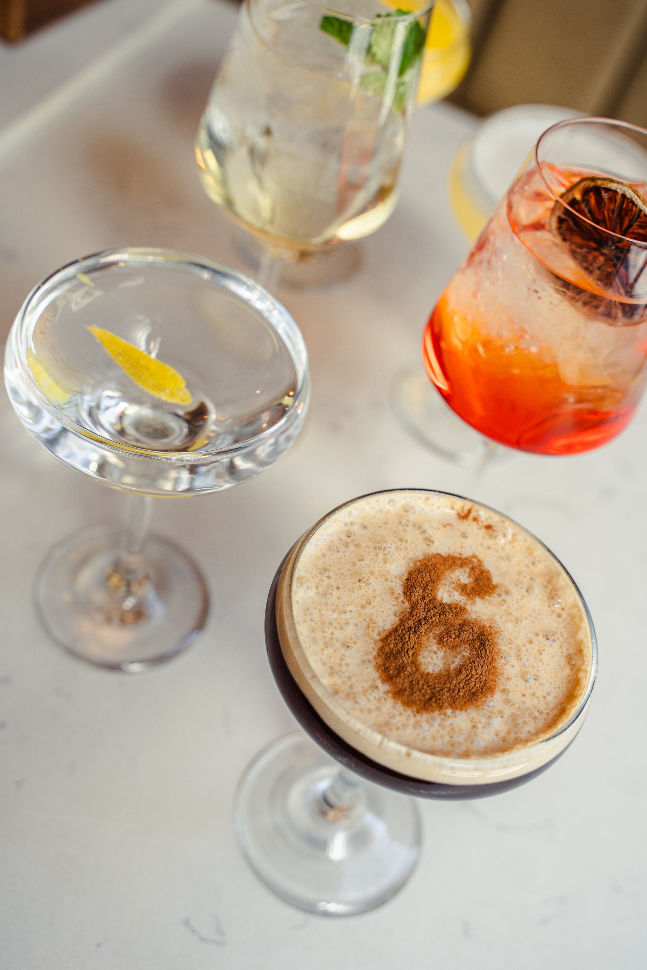 Espresso martini, classic martini, spritz, and Hugo Spritz served inside Eddy’s Kitchen, a cozy casual restaurant and cocktail bar in downtown Aspen.