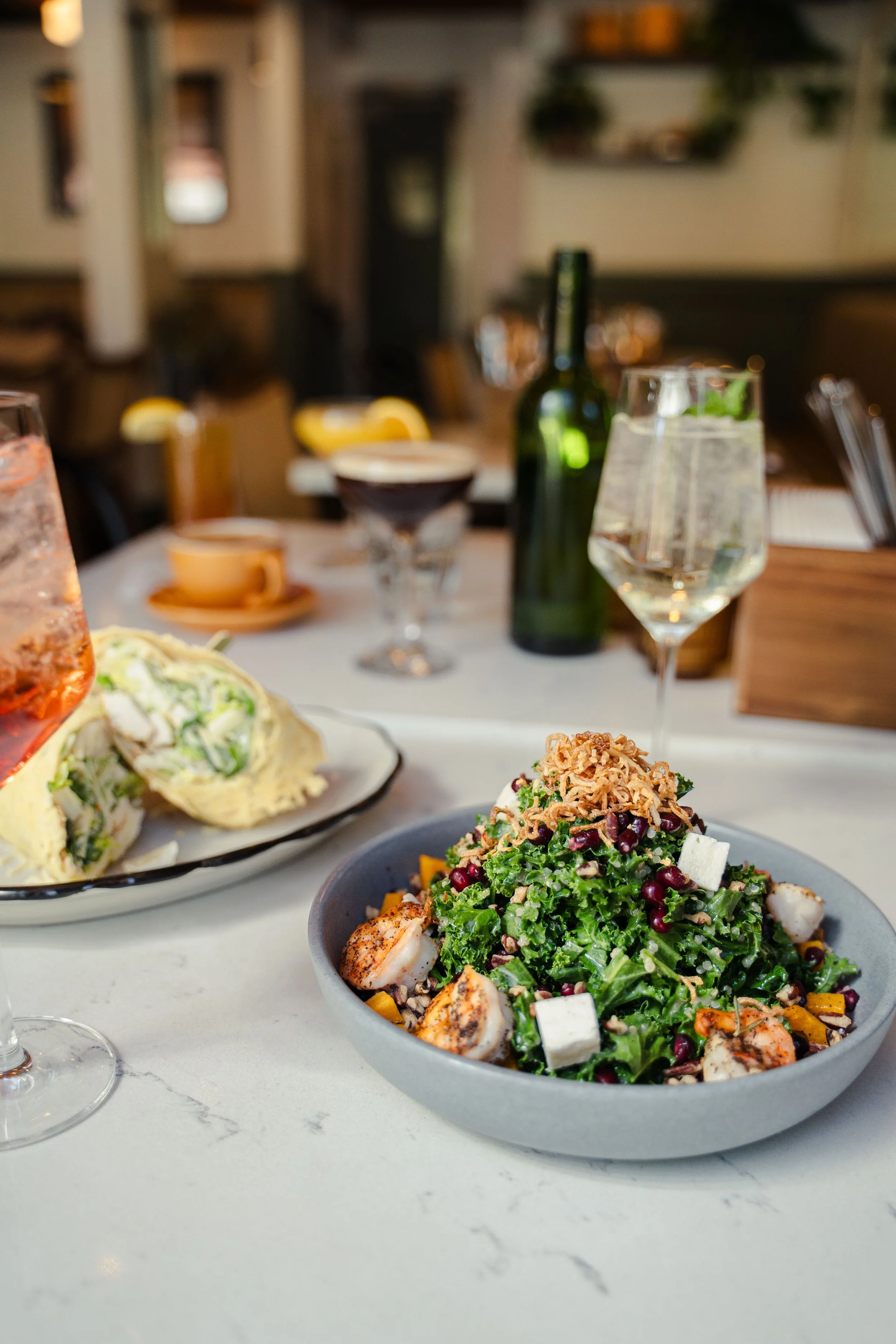 Kale and quinoa salad tossed in housemade apple cider vinaigrette with roasted butternut squash, pomegranate, feta, pecans, crispy shallots, and grilled shrimp at Eddy’s Kitchen in downtown Aspen.