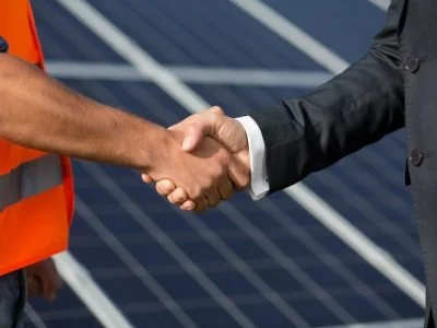 Close-up of two people shaking hands, one in a suit and the other in a high-visibility vest.