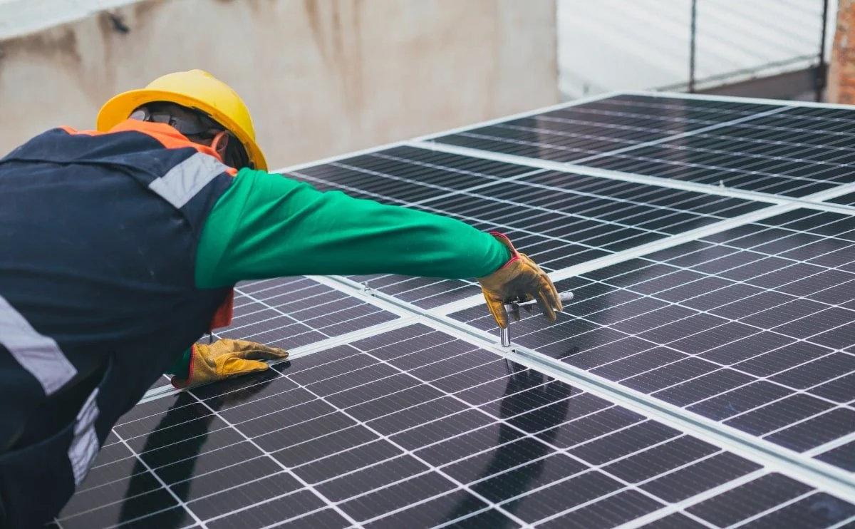 Man in Hard Hat and Safety Equipment Working on Solar Panel
