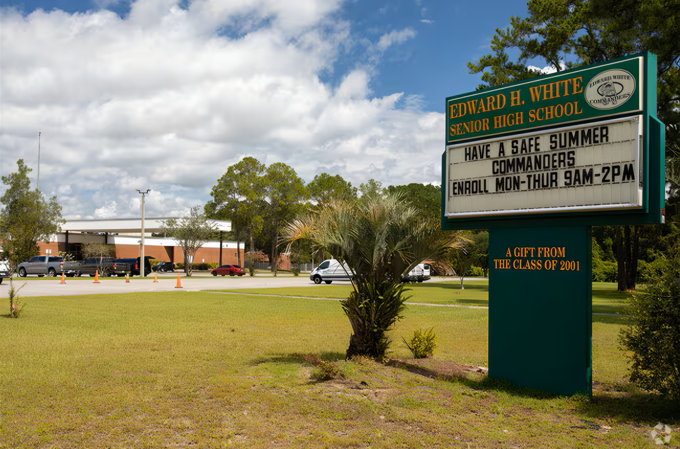 School sign for Edward H. White Senior High School with a message wishing a safe summer and details about enrollment hours, with trees, sky, and parked cars in the background.