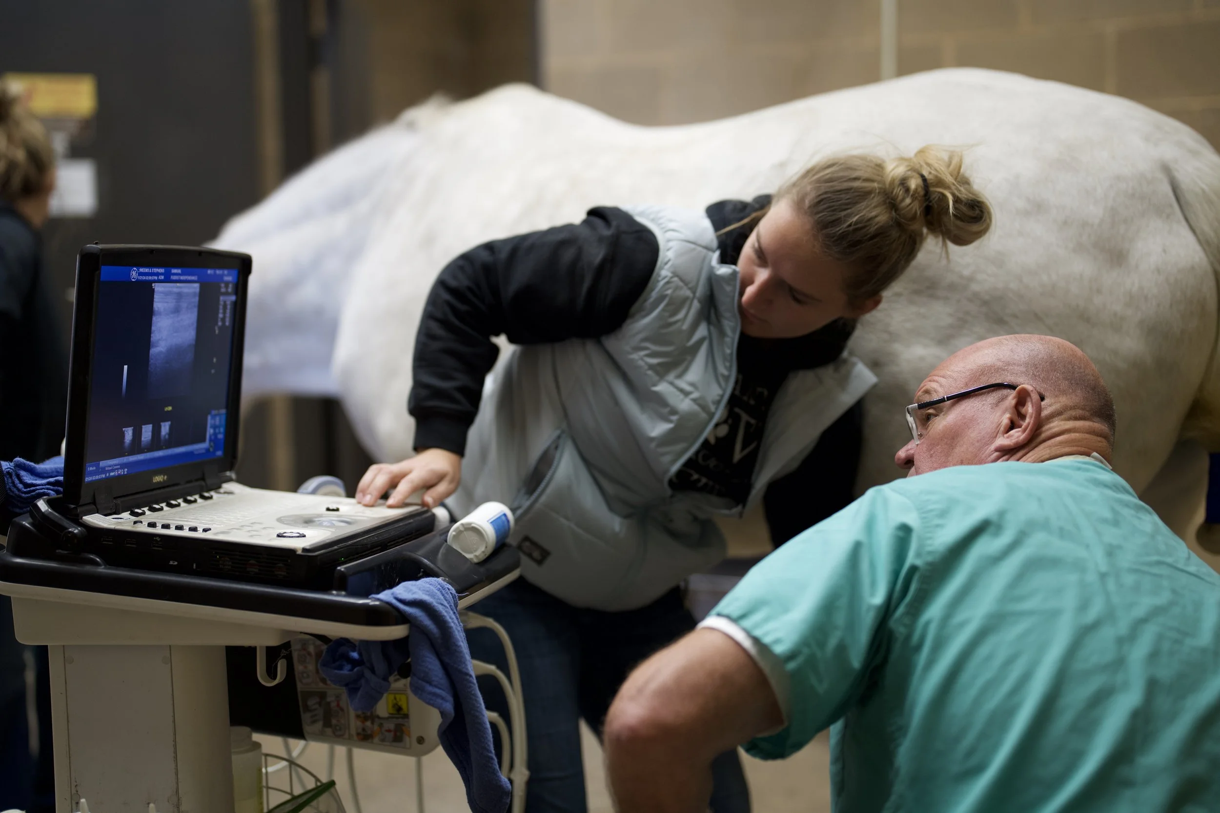 A person lying on a hospital bed being examined by a medical professional with ultrasound equipment.