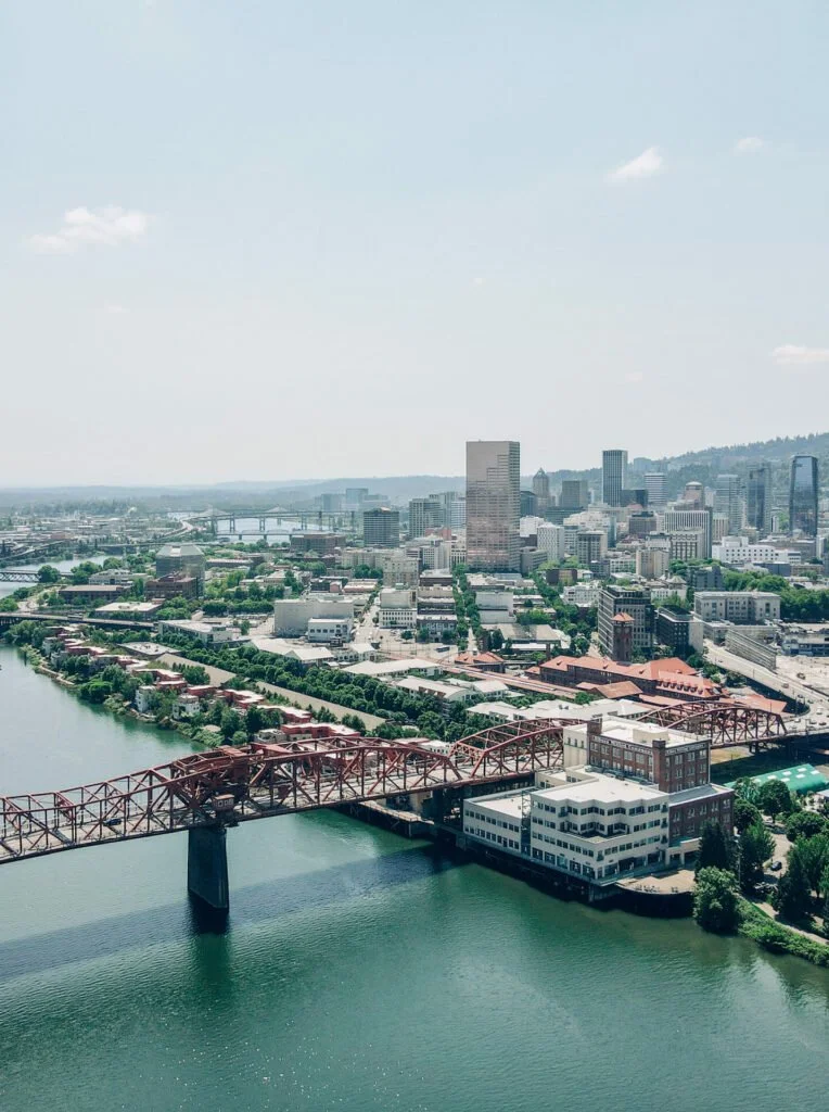 Aerial view of a city skyline with high-rise buildings, a bridge crossing a river, and a mostly clear sky with few clouds.