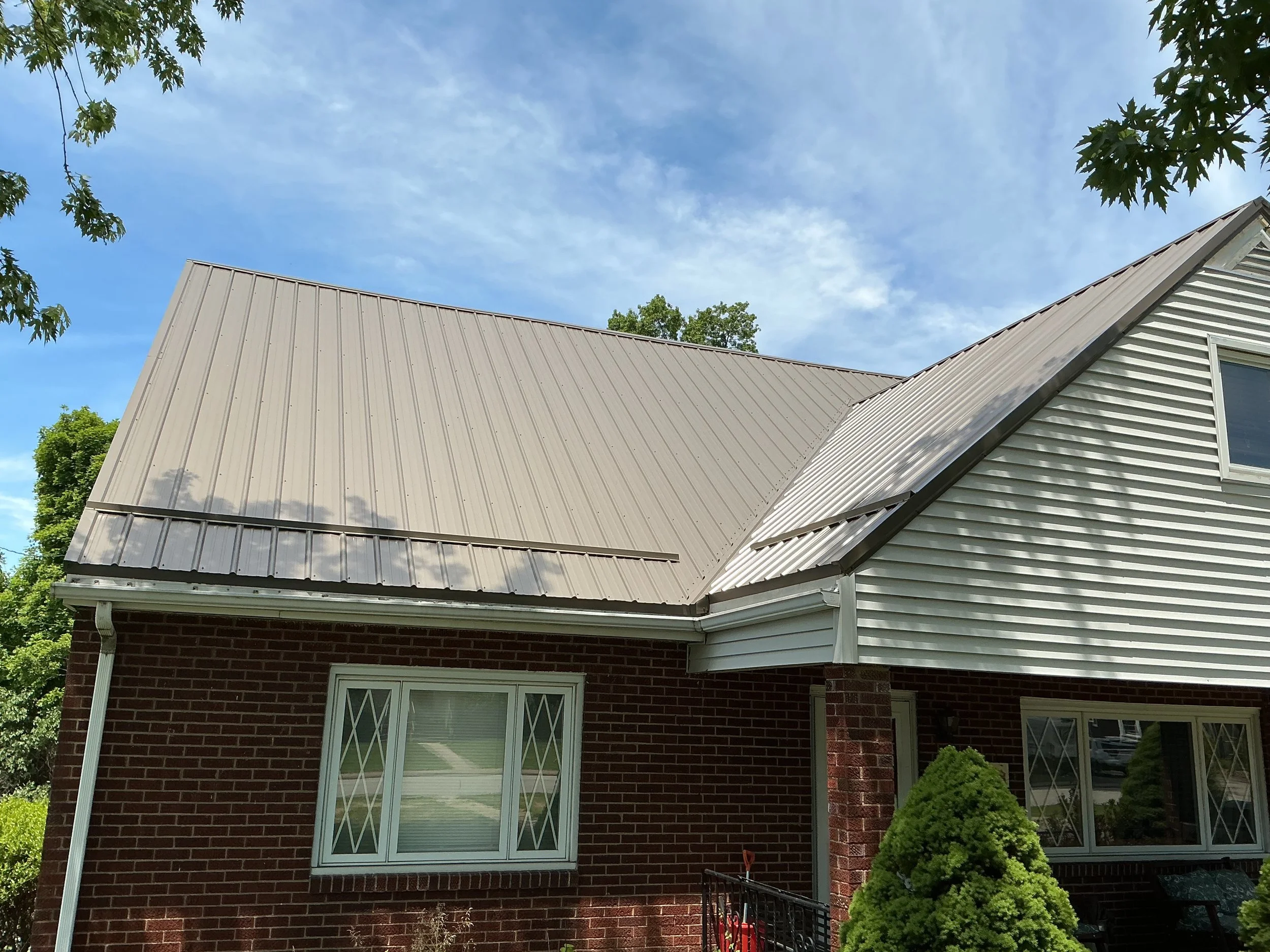 Brick ranch style house with a grey metal roof on a sunny day
