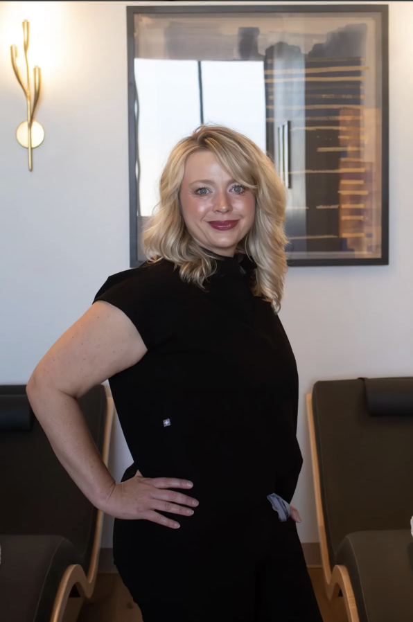 blonde woman with black scrubs smiling