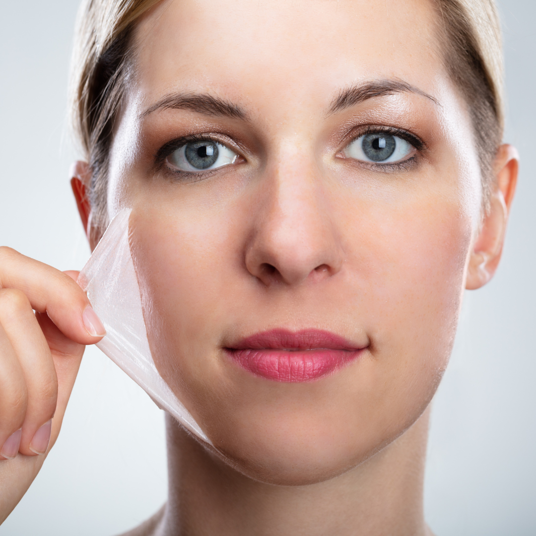 Woman peeling away a facial mask symbolizing common skincare myths being uncovered.