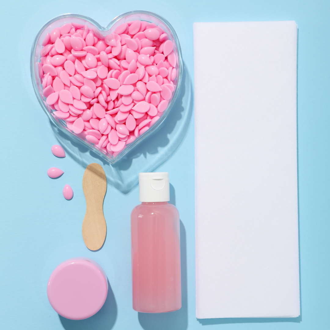 Waxing supplies arranged with pink wax, applicator, and waxing strips