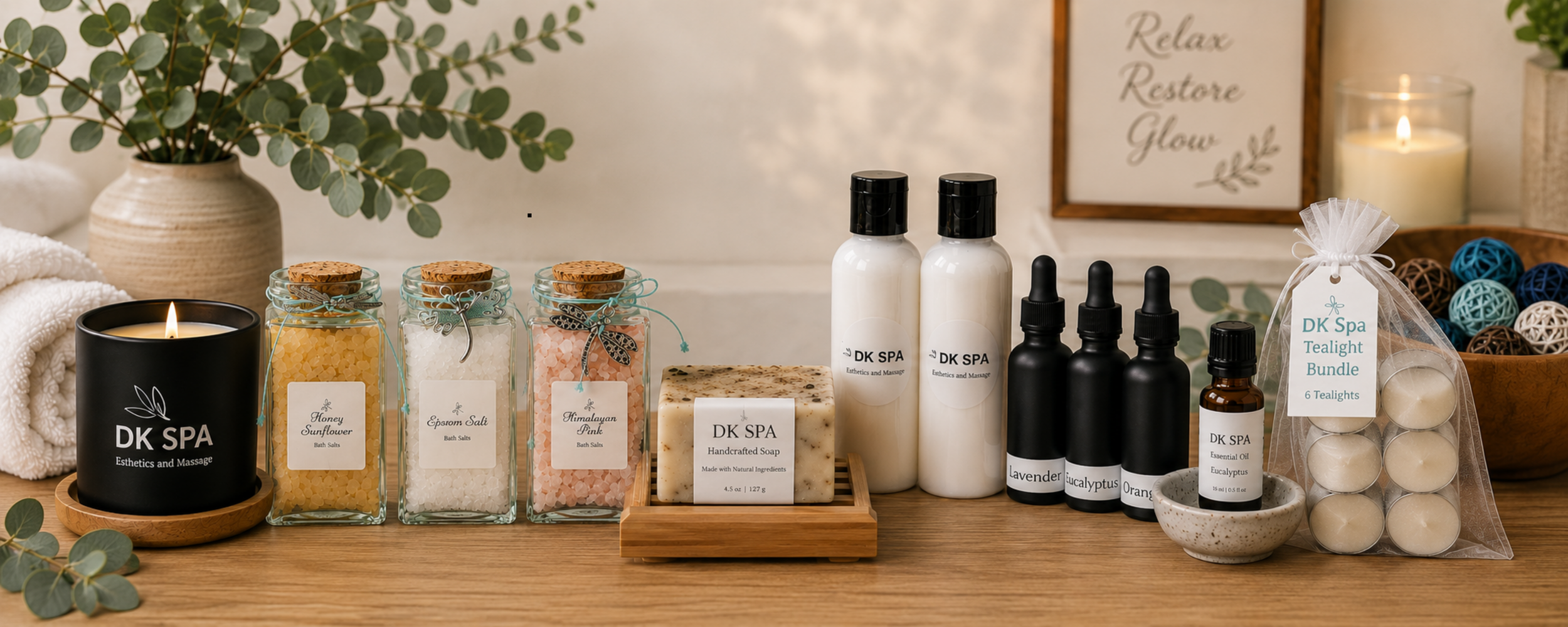 Collection of DK Spa handcrafted products including bath salts, soap, essential oils, lotion, candles, and a tealight bundle displayed in a relaxing spa setting.