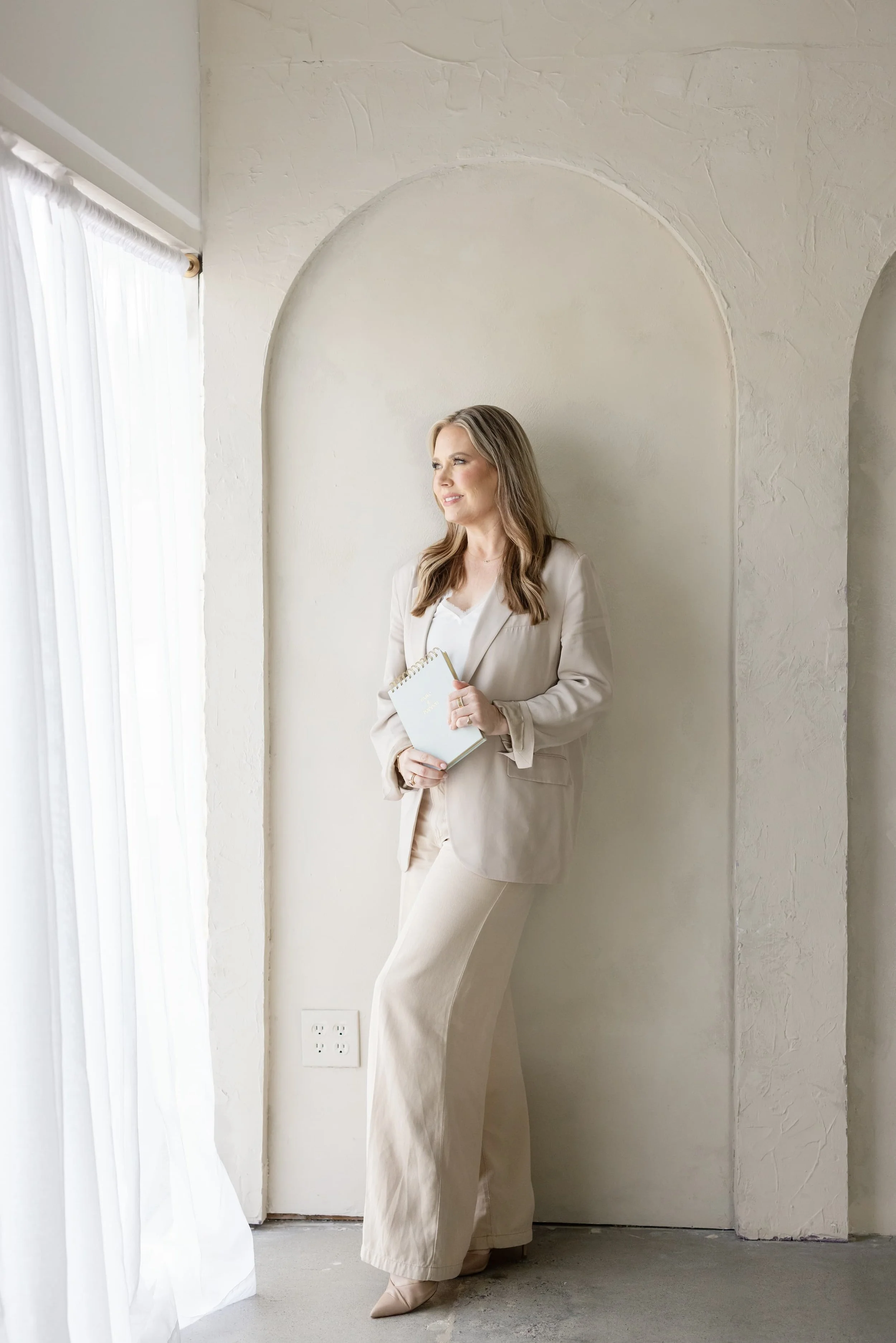 Susan Wrenn Licensed Therapist in California is standing and looking out the window in contemplation