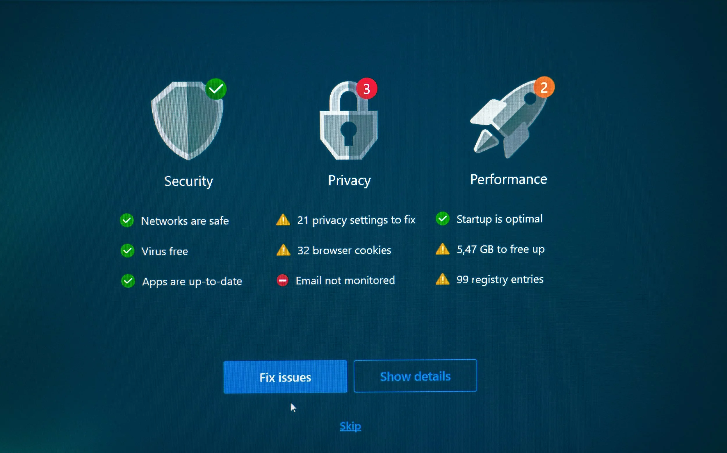 Computer screen displaying a security and privacy dashboard with icons of a shield, padlock, and rocket. The dashboard shows status indicators such as networks being safe, viruses free, and apps up-to-date, alongside warnings for privacy settings, browser cookies, free storage, email monitoring, and registry entries. Buttons to fix issues or show details are visible, with an option to skip at the bottom.