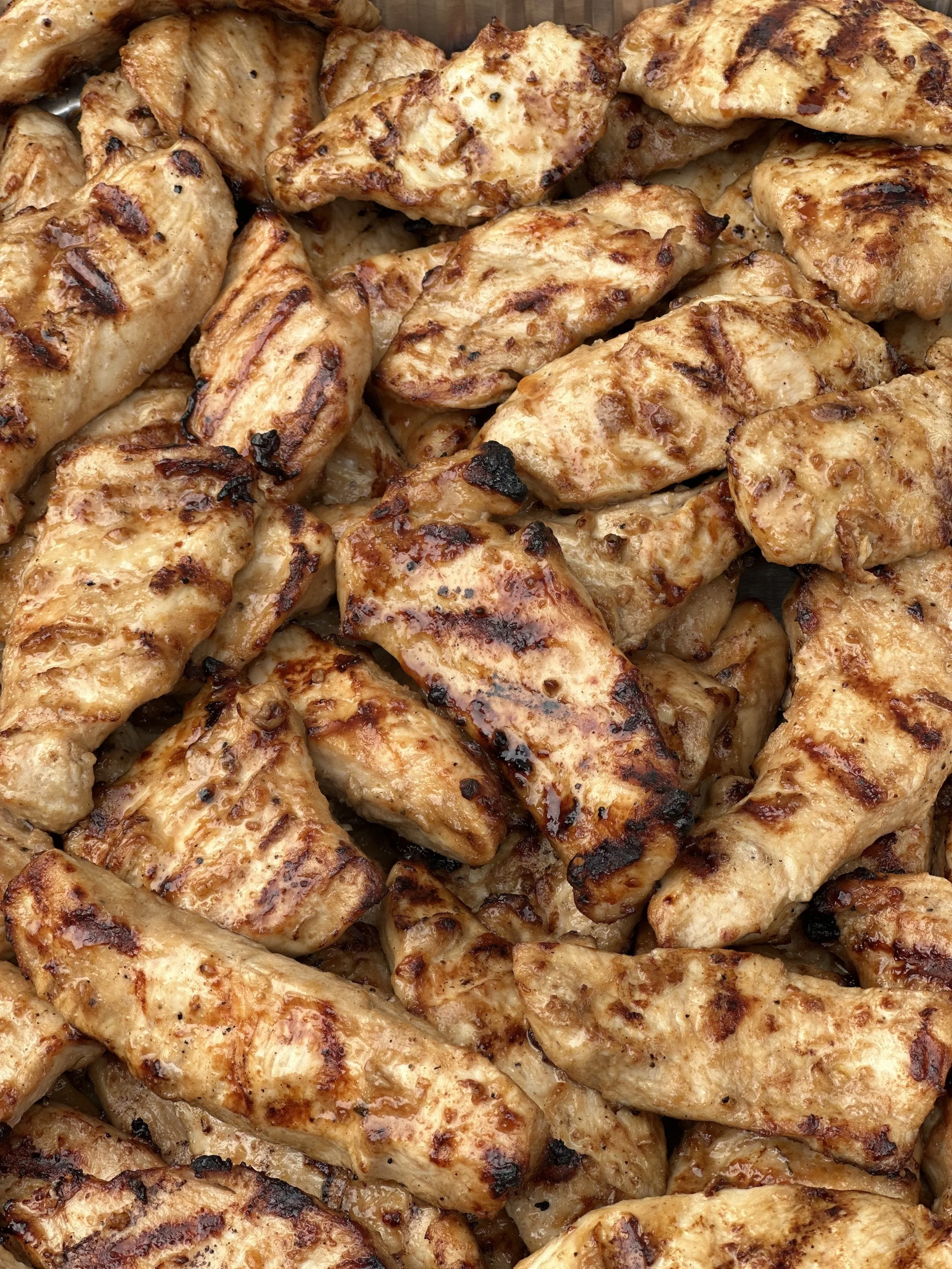 Close-up of grilled chicken pieces with charred grill marks and a glaze.