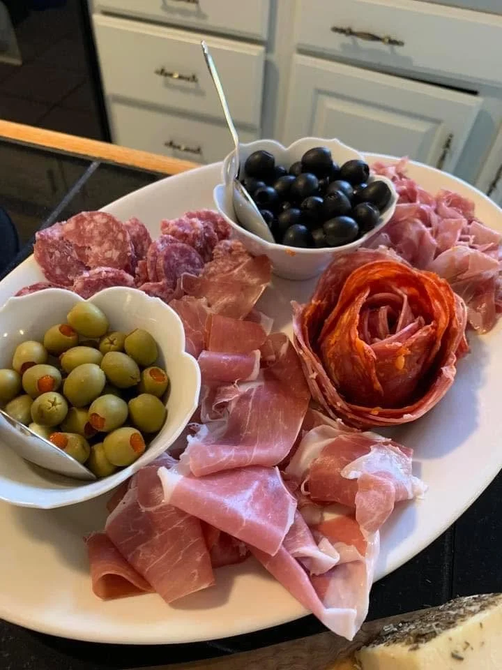 Charcuterie platter with assorted meats, green and black olives, and a small bowl of blueberries.