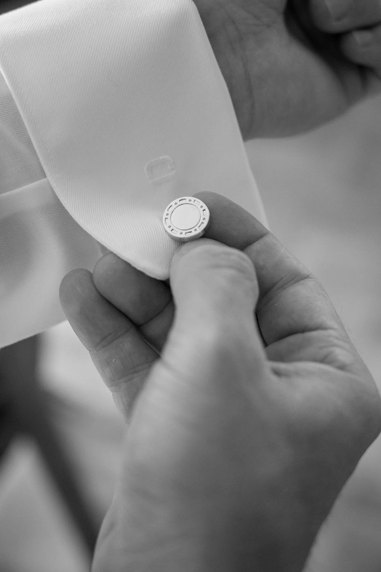 Nahaufnahme einer Hand, die eine kleine runde Gegenstand hält, der möglicherweise ein Chip oder eine Münze ist. Die Person trägt ein weißes Kleidungsstück.