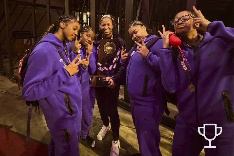 Group of five young girls in matching purple hoodies and pants, holding a trophy and medals, celebrating an achievement.