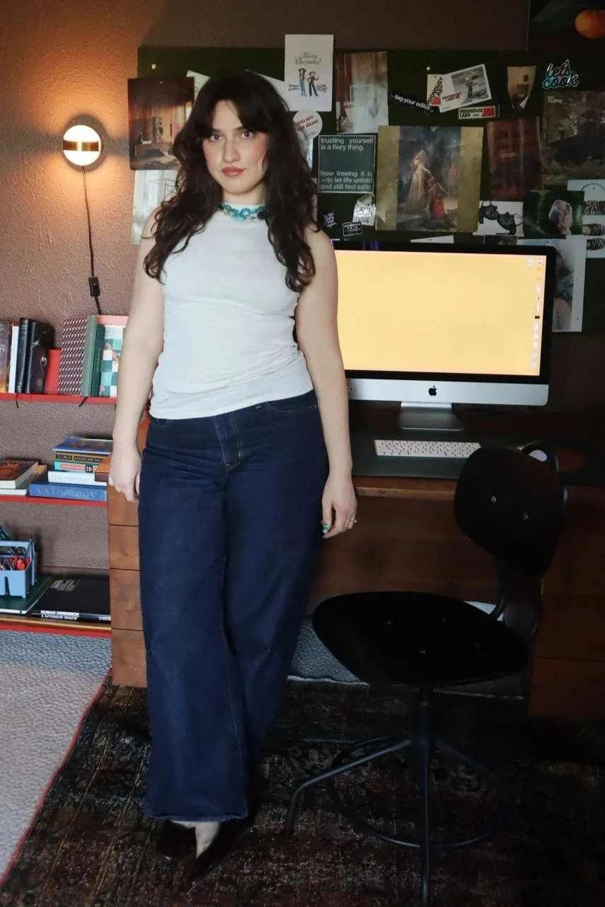 sighthound founder Kaitlin Veltri stands in front of her office desk and bulletin board with design references in a brown office