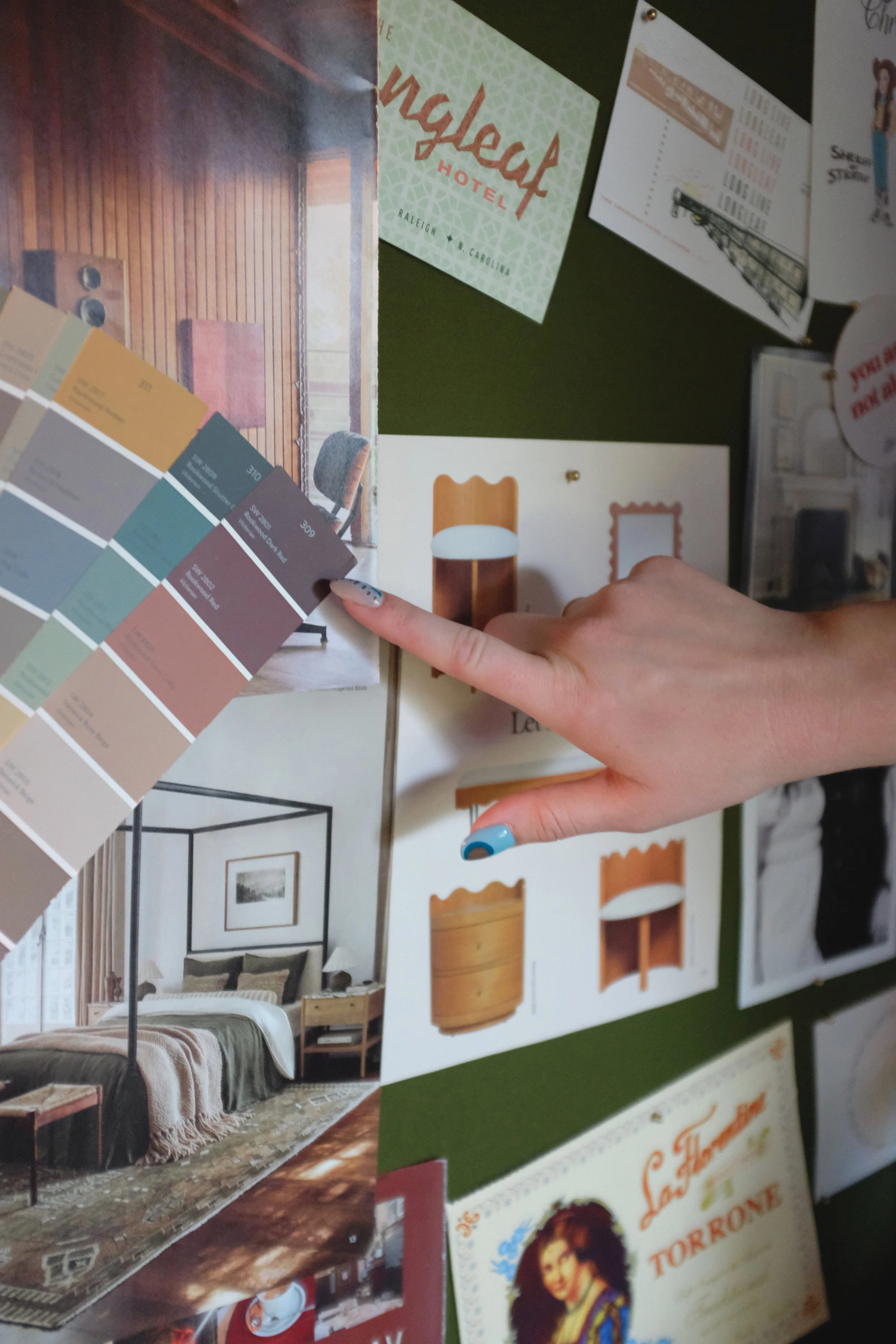 close up of interior decorator hand pointing at paint chips on a bulletin board