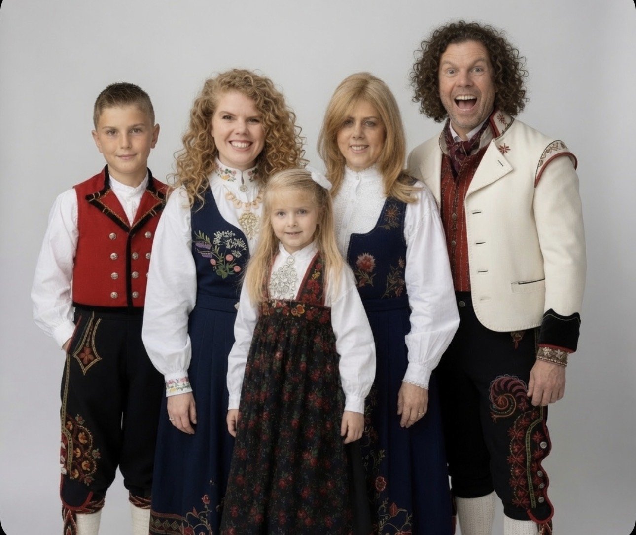 Six people dressed in traditional Scandinavian or Eastern European folk attire, standing in front of a plain white background, smiling for the photo.
