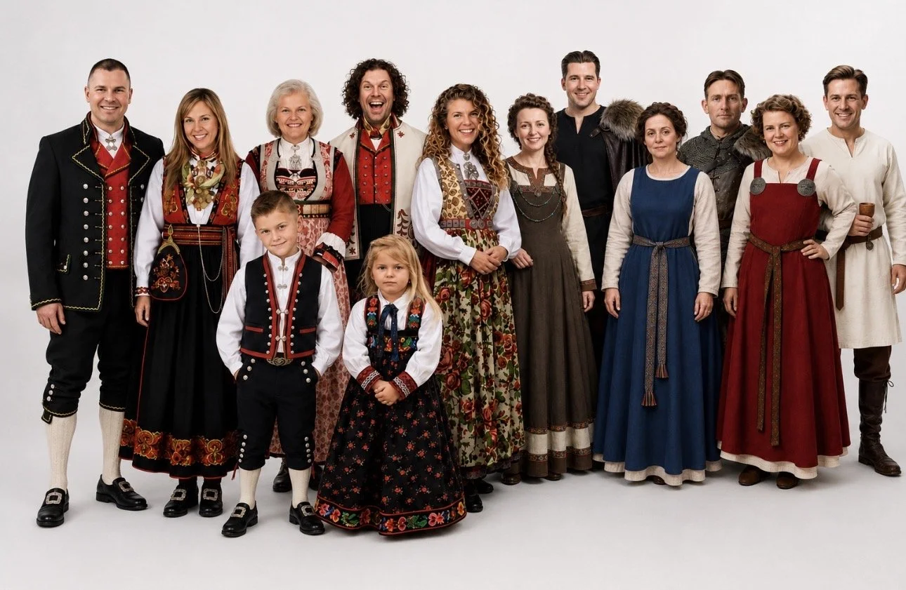 Group of people wearing traditional European folk costumes, standing together and smiling against a plain white background.