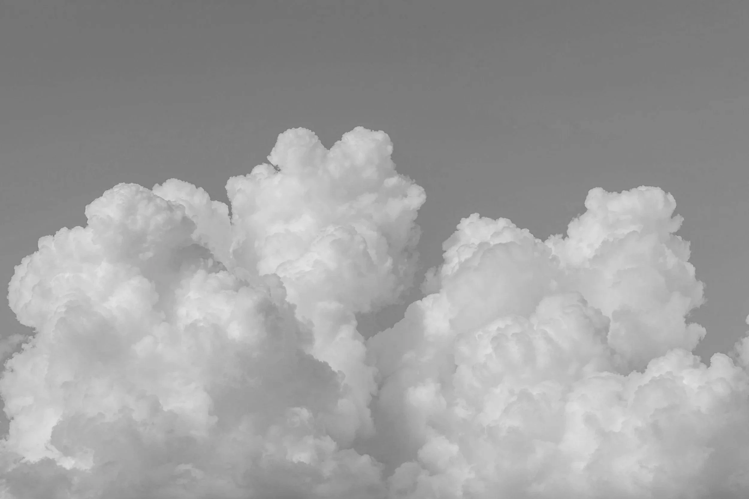 Black and white photo of fluffy clouds in the sky.