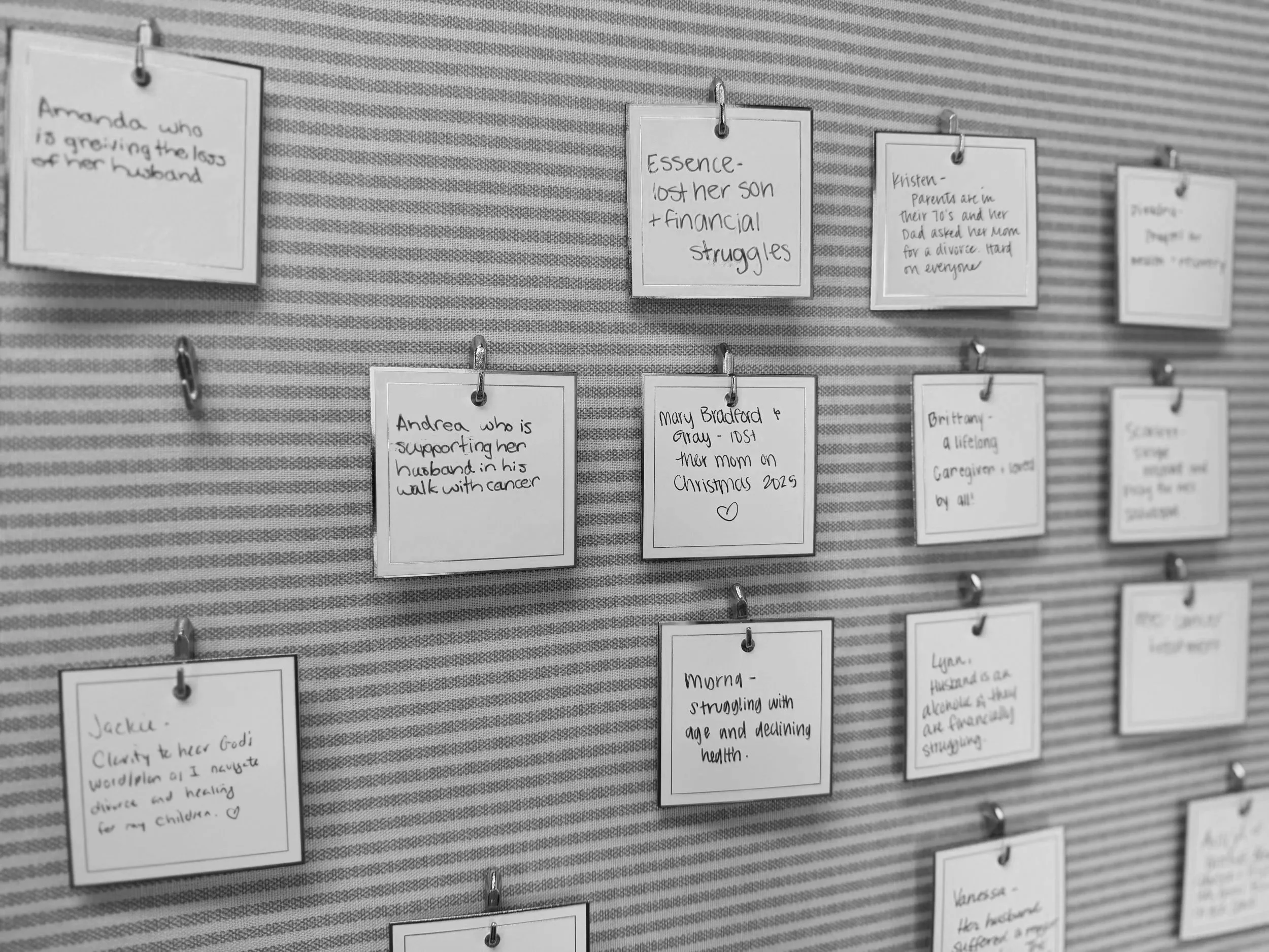 Multiple notes hanging on a wall with what people are struggling with, including financial struggles, supporting a spouse, grief, and aging health issues.