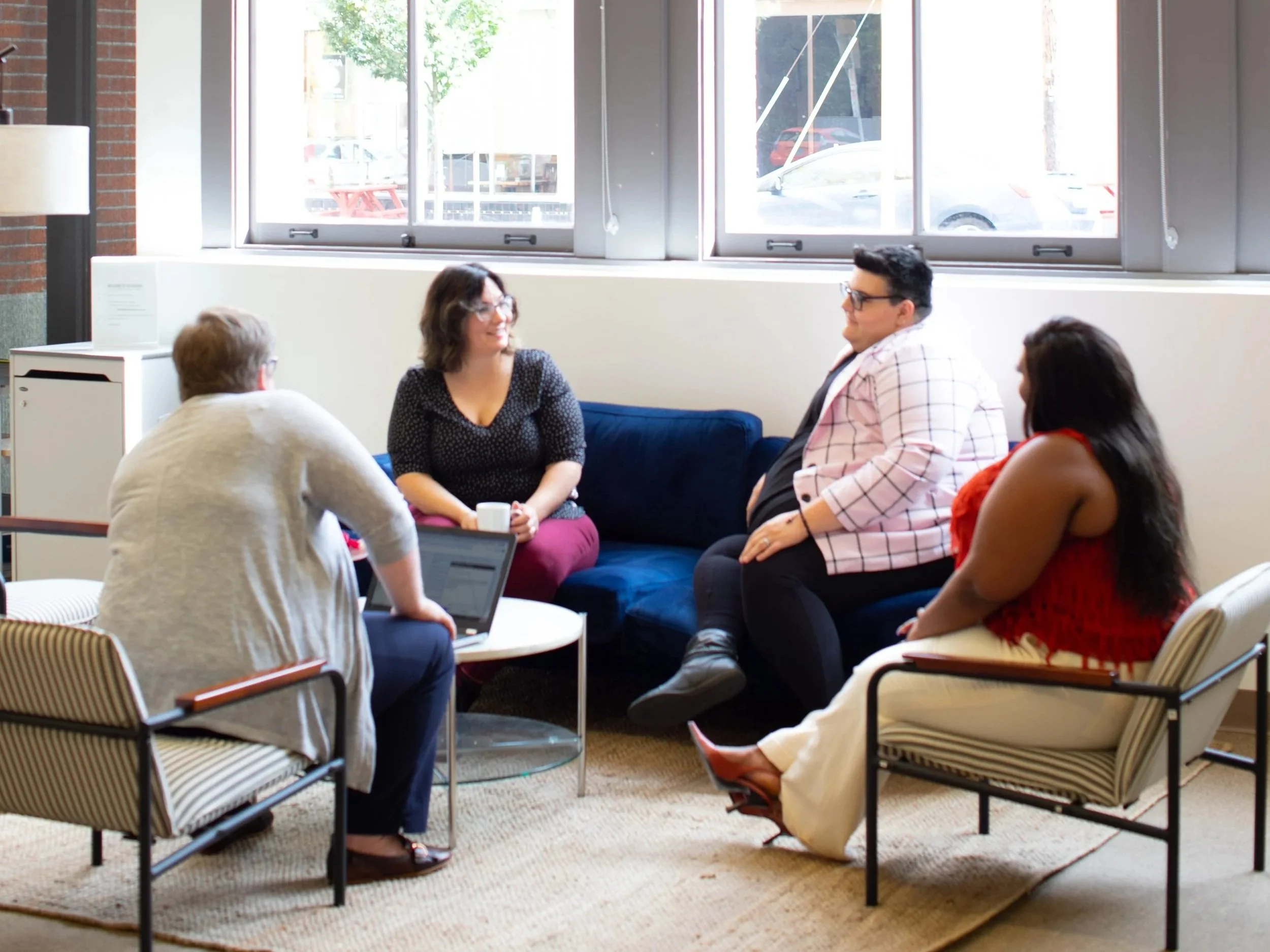 A vibrant gathering of diverse individuals filled with energy, sharing laughter and ideas in a sunlit room, celebrating body positivity and fat liberation amidst a cozy, inviting atmosphere.