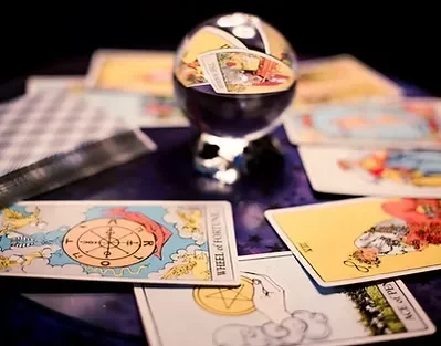 Tarot cards laid out on a table with a black candle and some coins or jewelry nearby.
