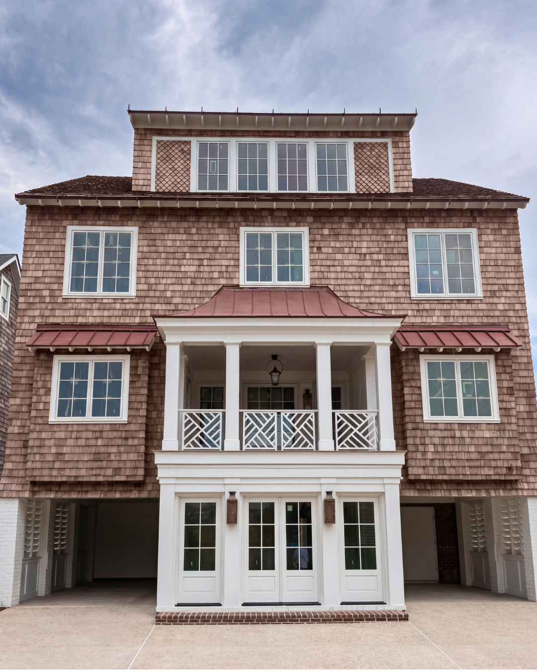 Front view of a multi-story house with shingled exterior, white accents, and a small covered porch with white railings.
