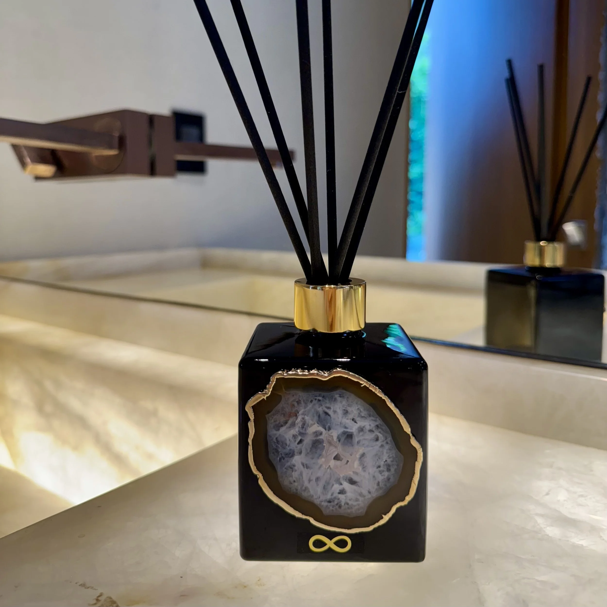 Close-up of a modern reed diffuser with a luxurious agate cristal slice on top in a powder room.
