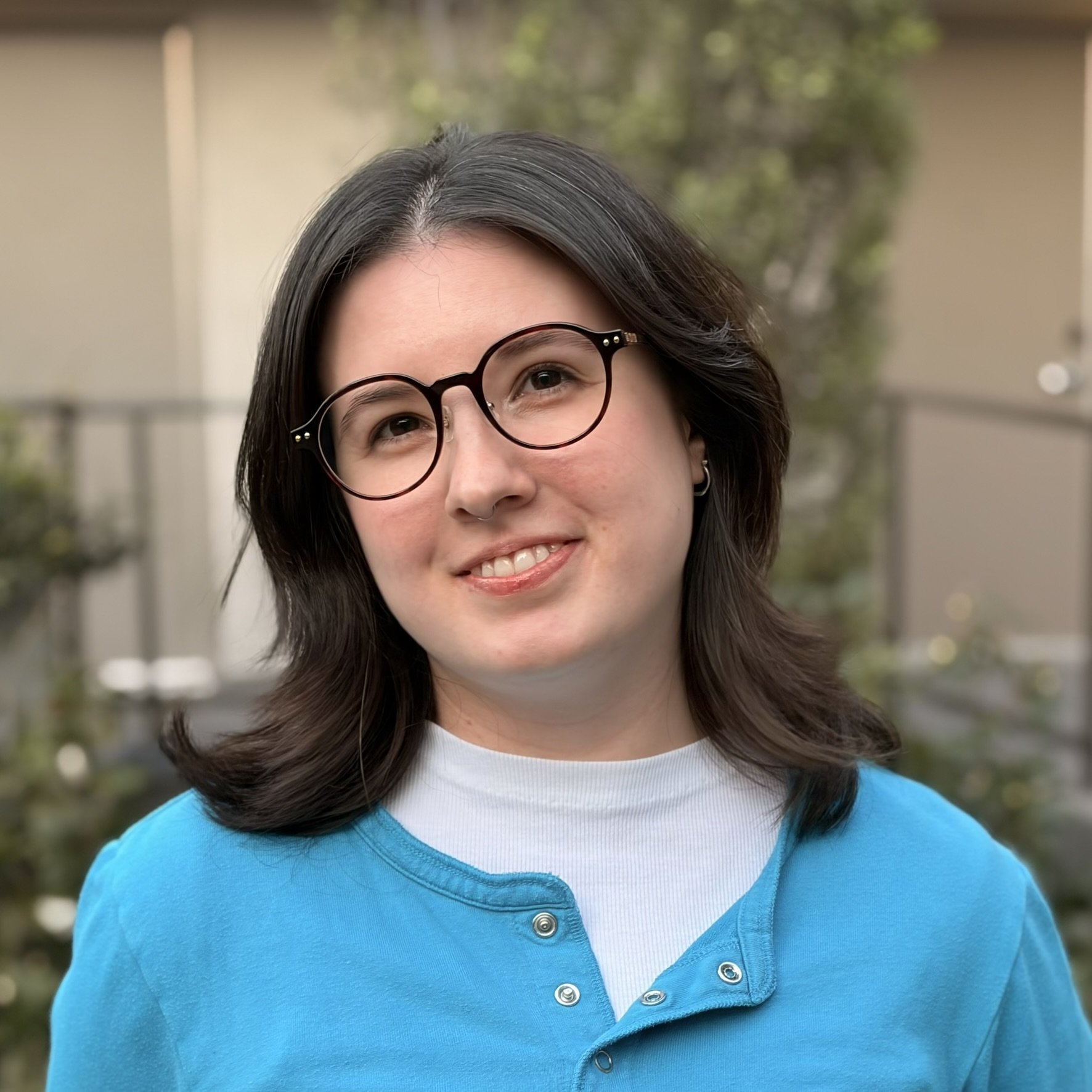 Image of Maile Aihua Young in a white and blue shirt, outdoors and smiling at the camera