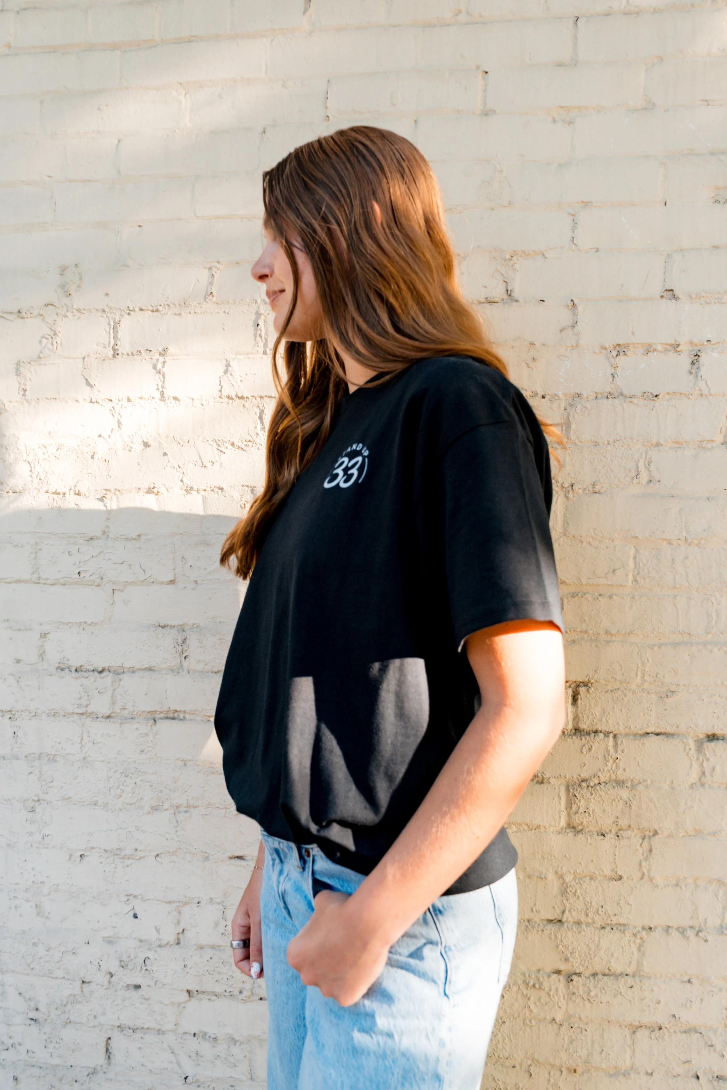 Side view of a person wearing a StandUp33 T-shirt with the StandUp33 logo.