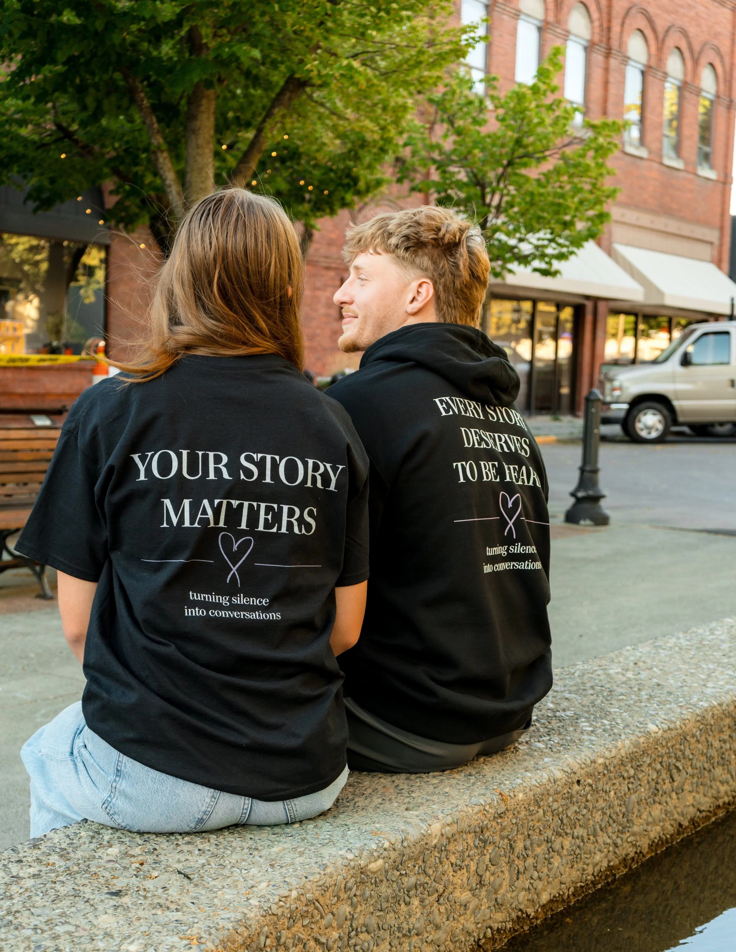 Two people wearing StandUp33 awareness apparel while sitting and talking outdoors.