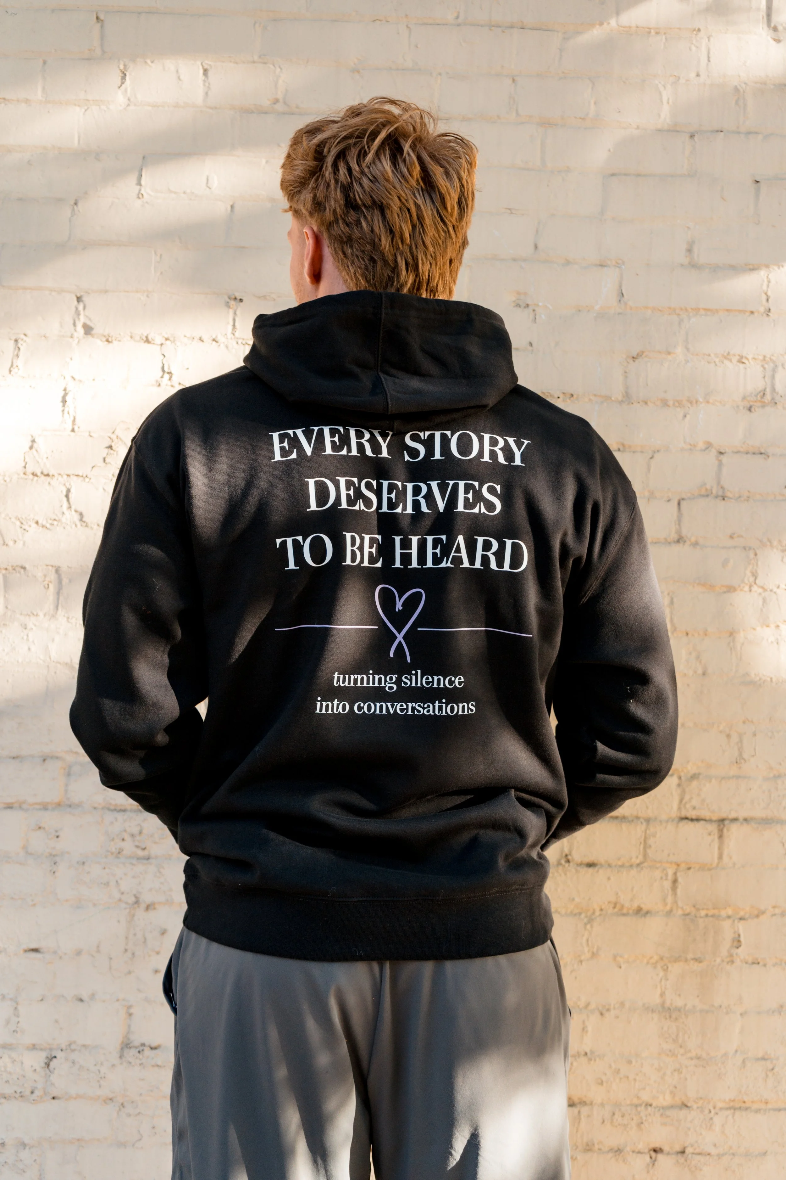 Back of StandUp33 hoodie featuring the message, "Every Story Deserves to Be Heard," with a purple heart design.