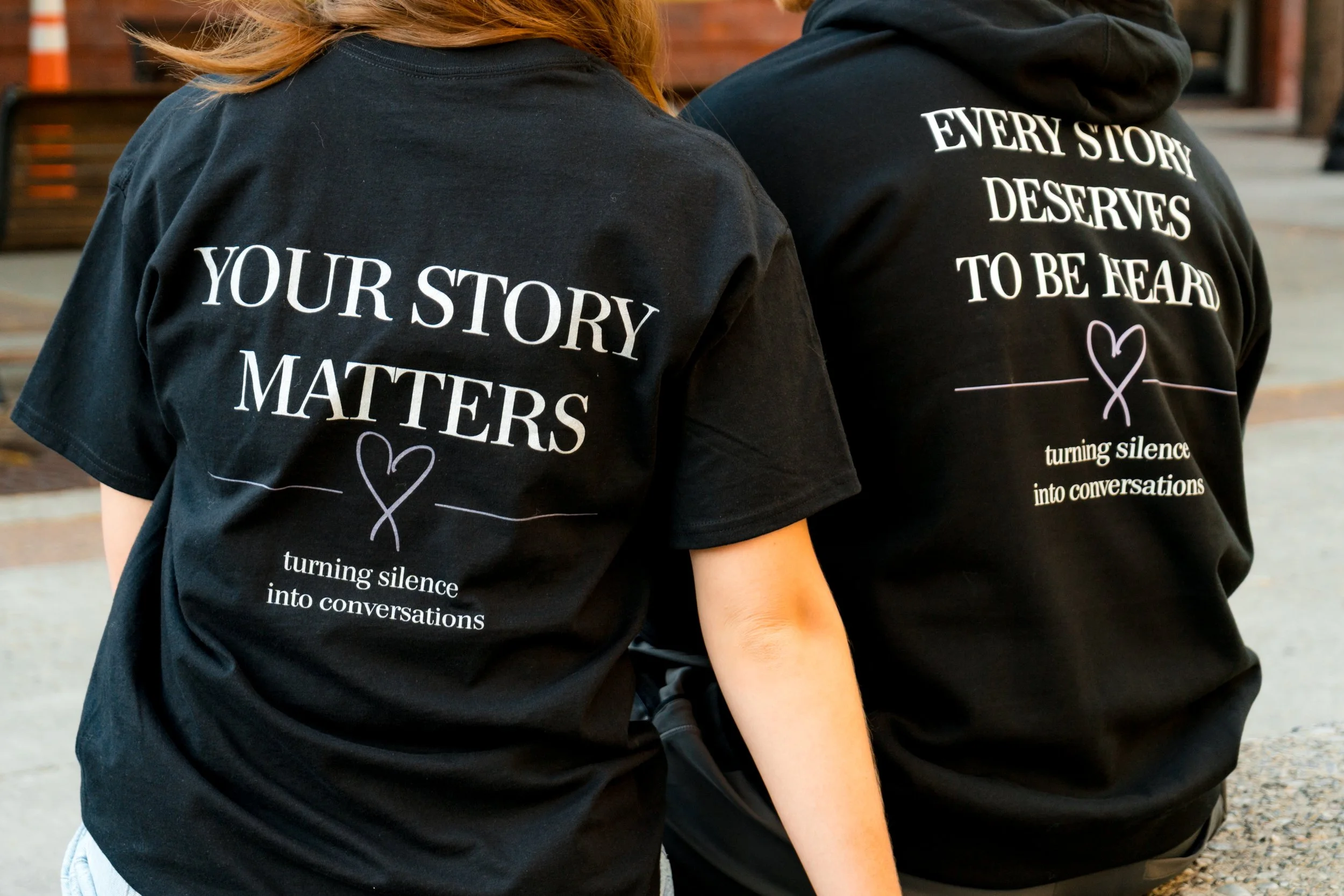 Backs of two people wearing StandUp33 T-shirts displaying awareness messages.