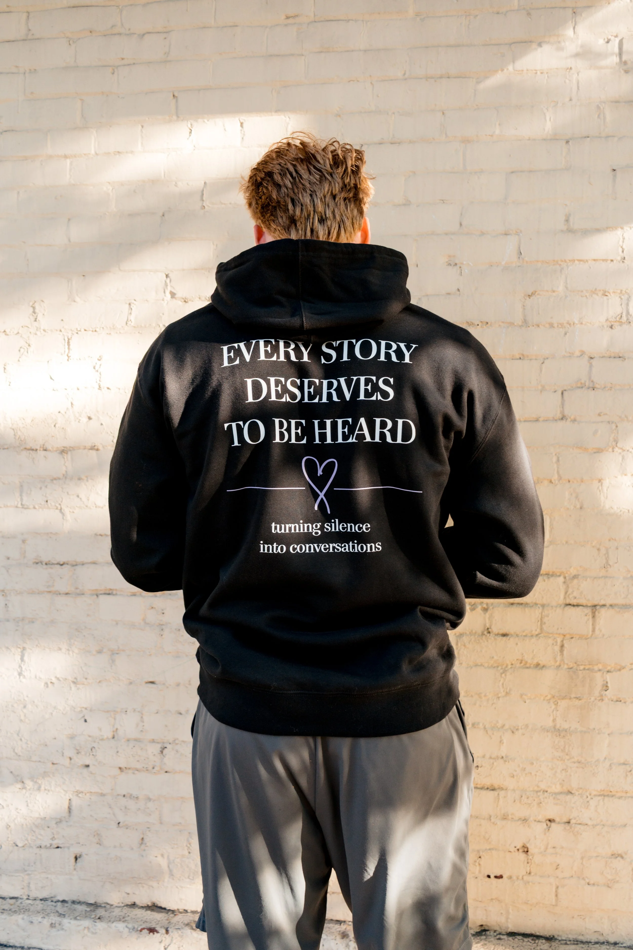 Back of a StandUp33 hoodie displaying the messages, "Every Story Deserves to Be Heard," and "Turning Silence into Conversations."