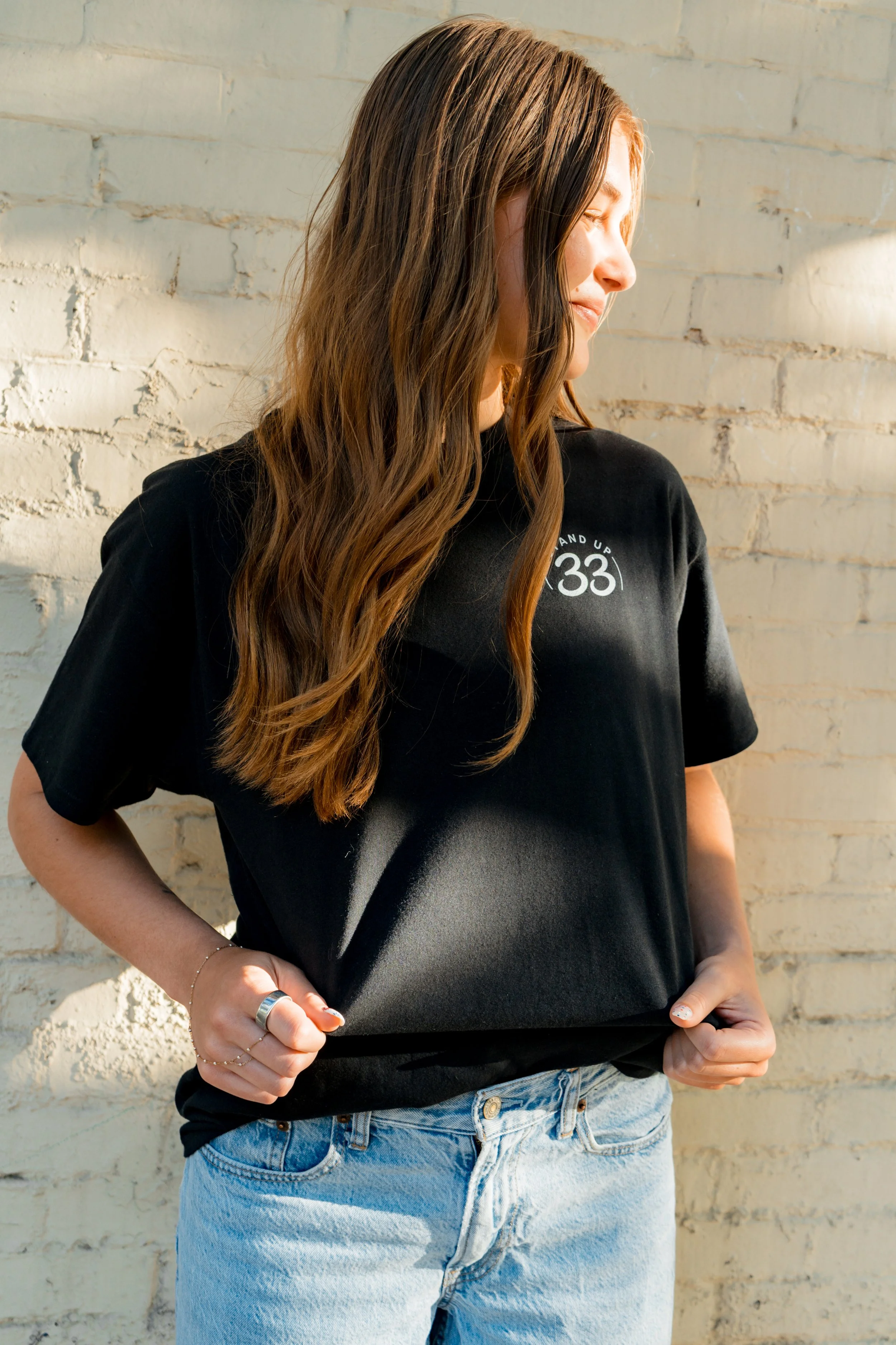 Side view of a person wearing a StandUp33 T-shirt with the StandUp33 logo.