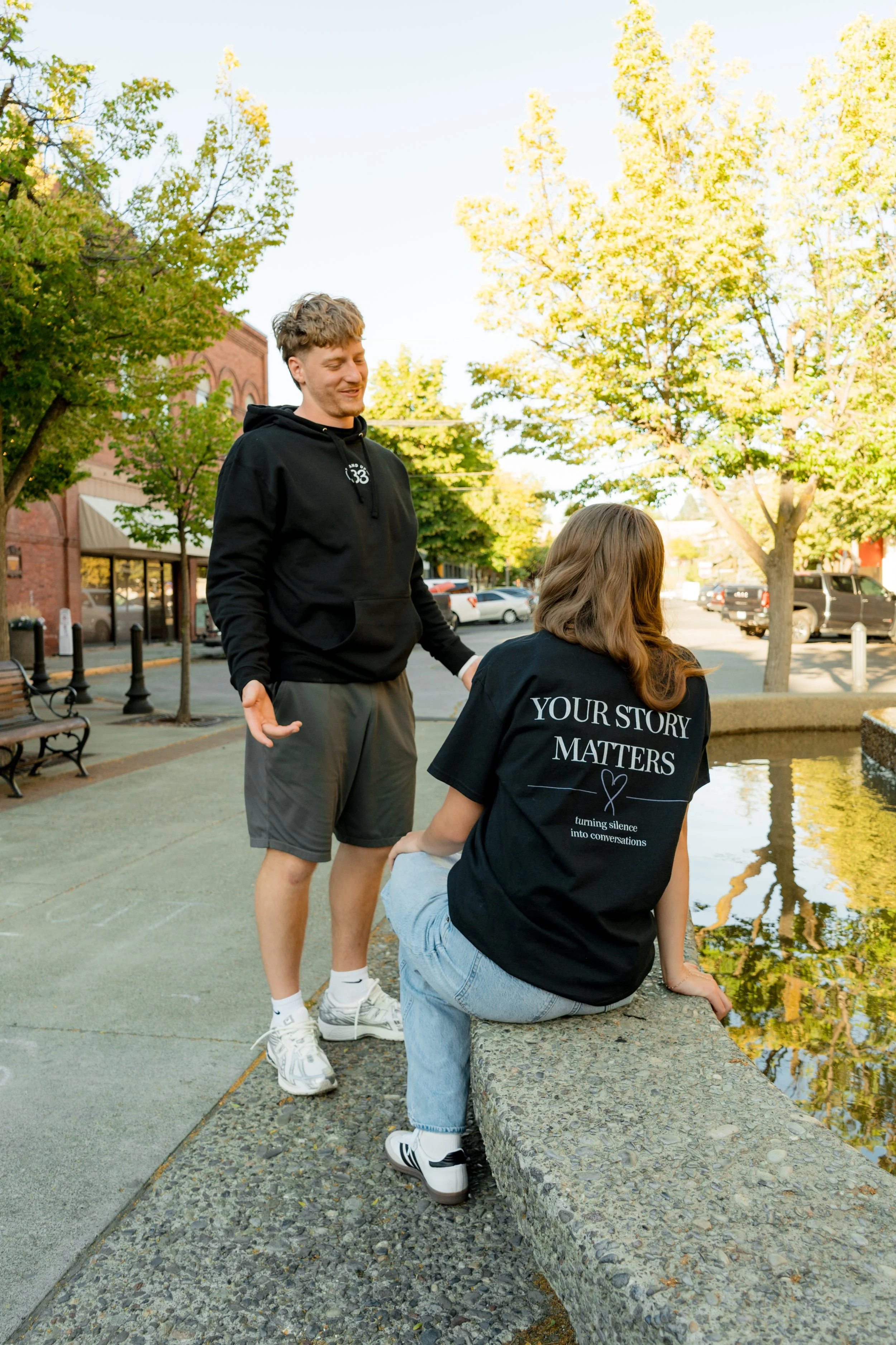 Two people wearing StandUp33 awareness apparel while standing near a fountain.