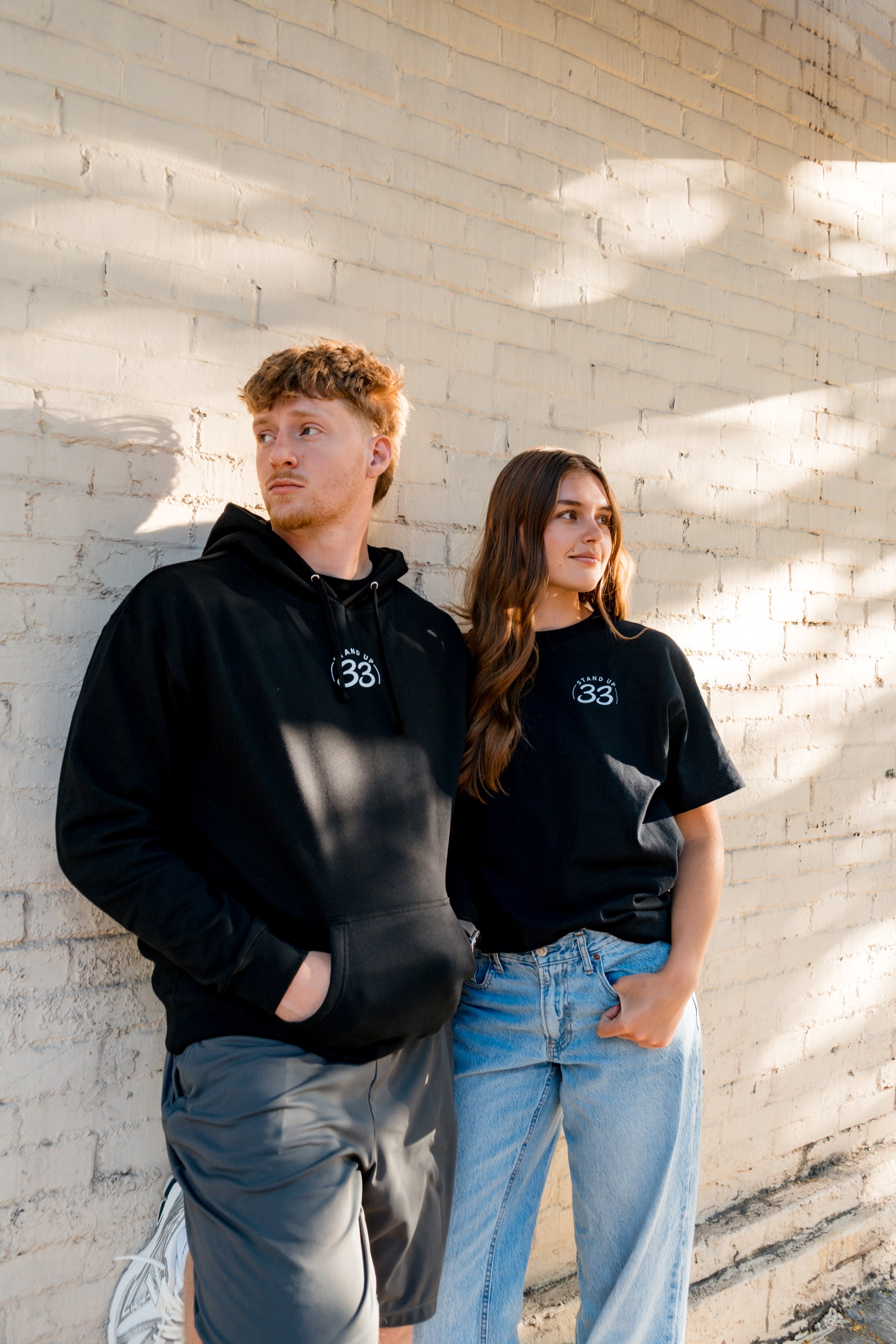 Two people wearing StandUp33 awareness hoodies that encourage difficult but necessary conversations.
