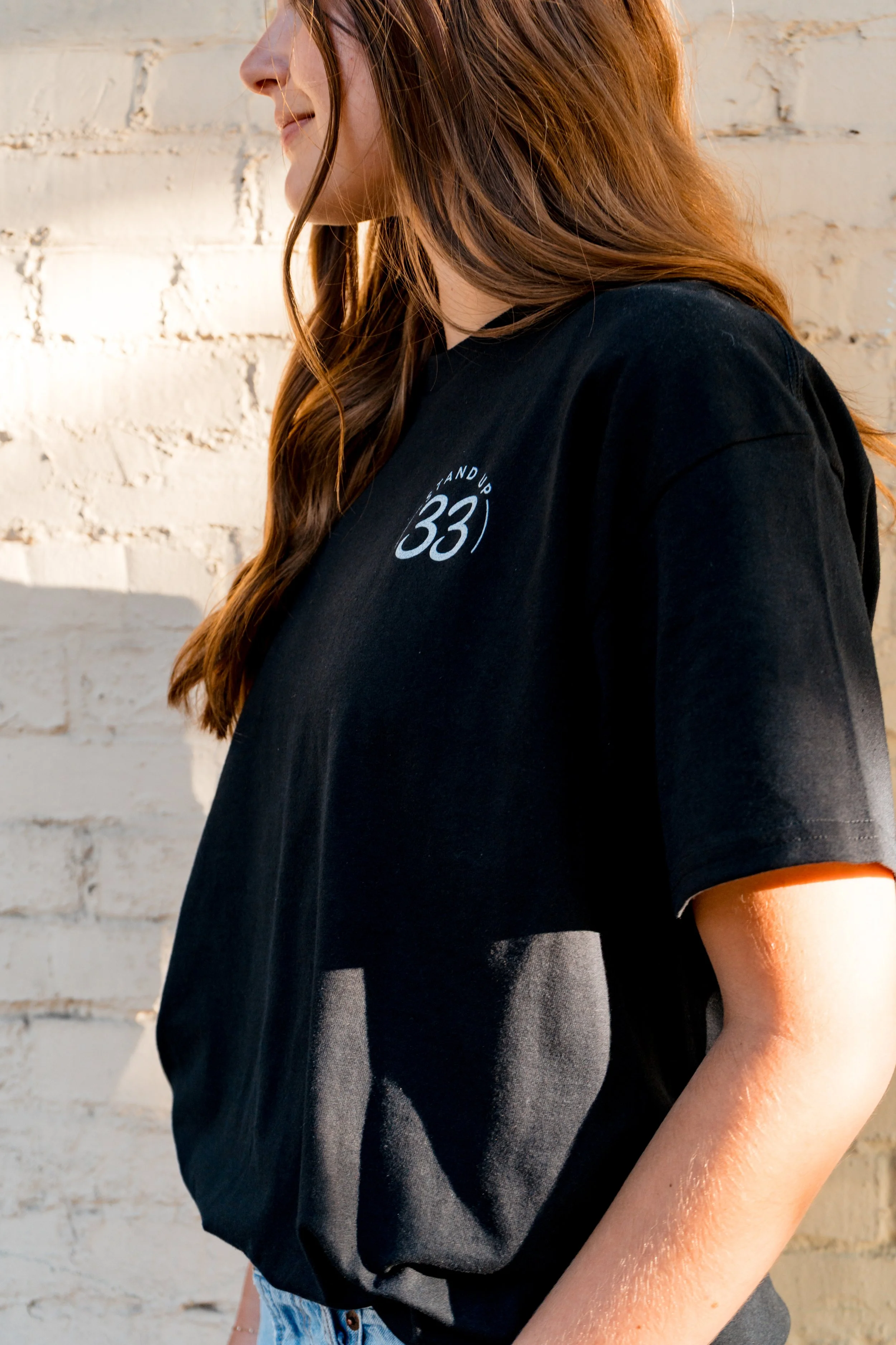 Close-up of the front of a person wearing a StandUp33 T-shirt with the StandUp33 logo.