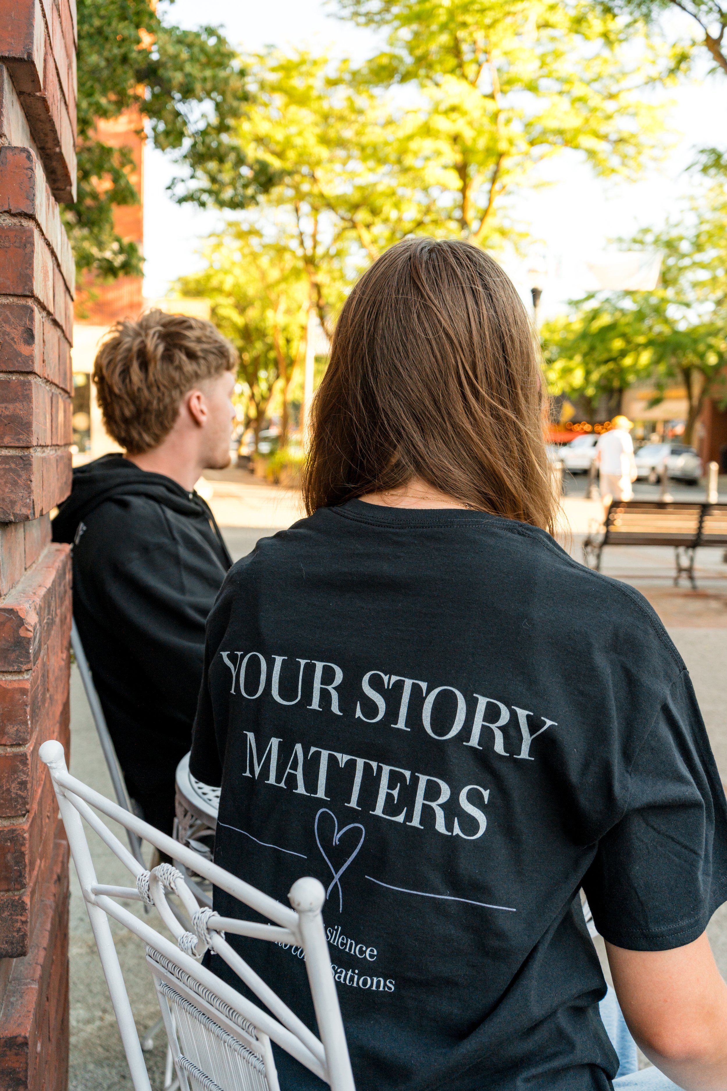 Two people wearing StandUp33 awareness apparel while sitting together on a park bench.