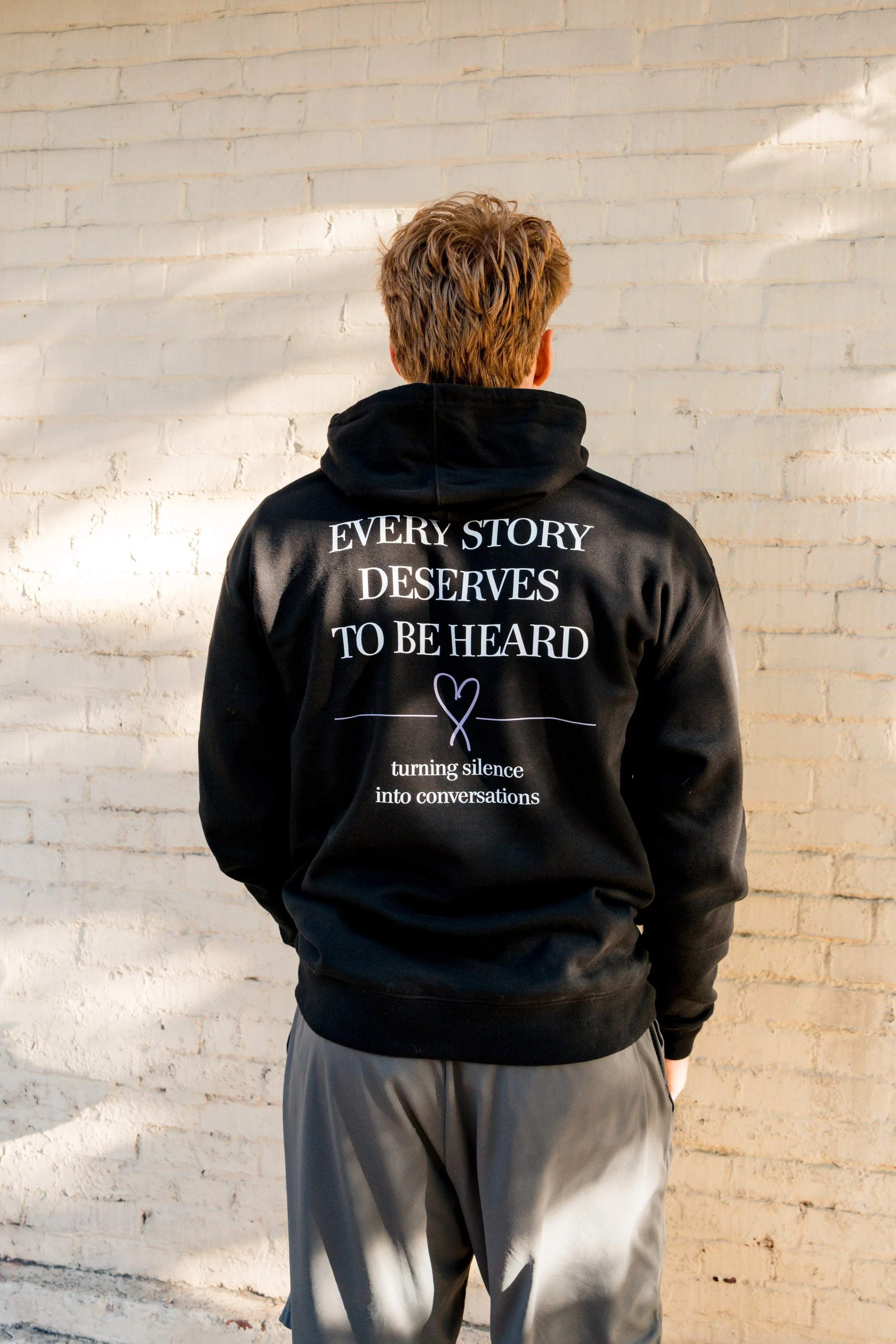 Back of a person wearing a StandUp33 hoodie displaying the message, "Every Story Deserves to Be Heard."