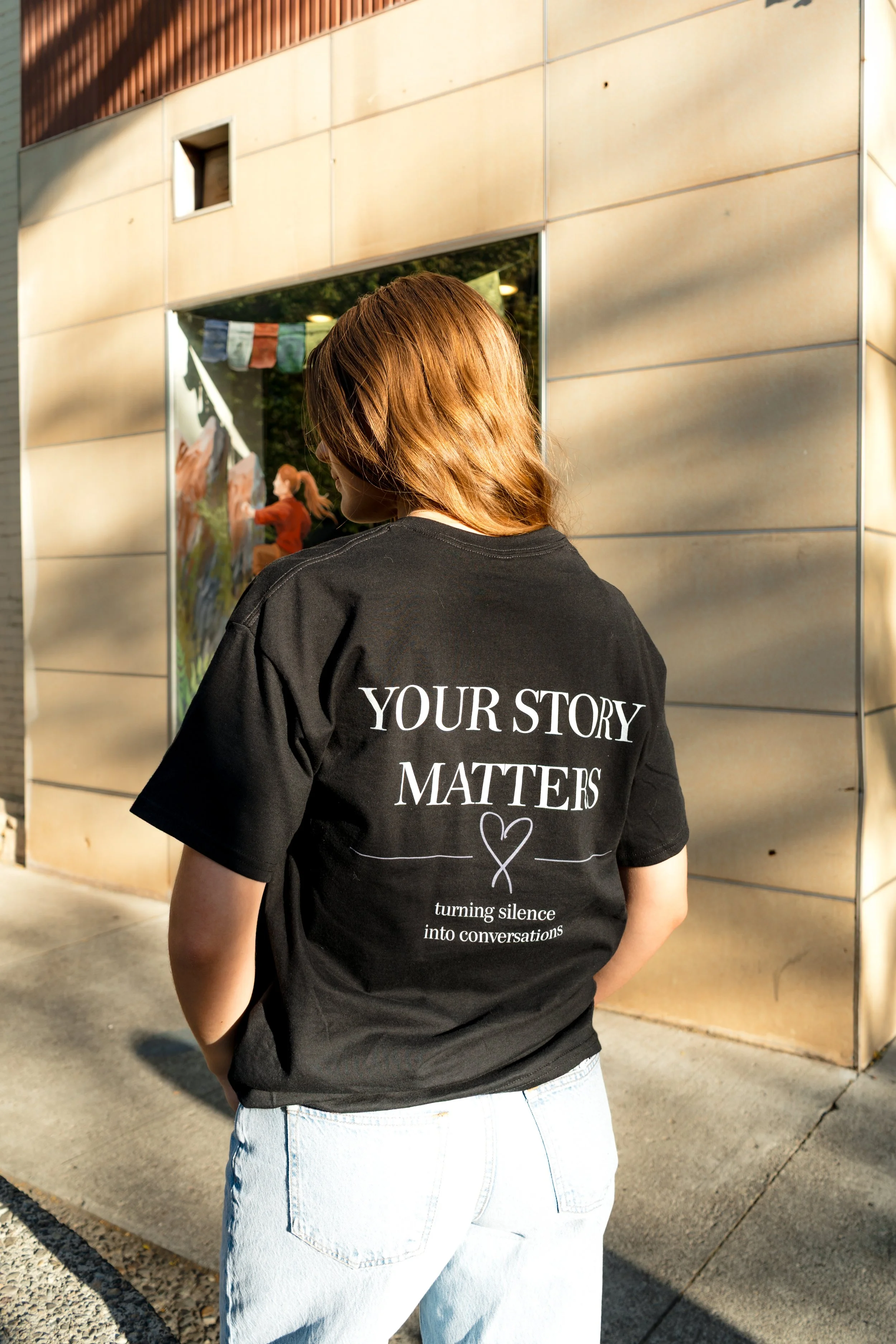 Woman wearing a StandUp33 "Your Story Matters" T-shirt while standing outdoors.