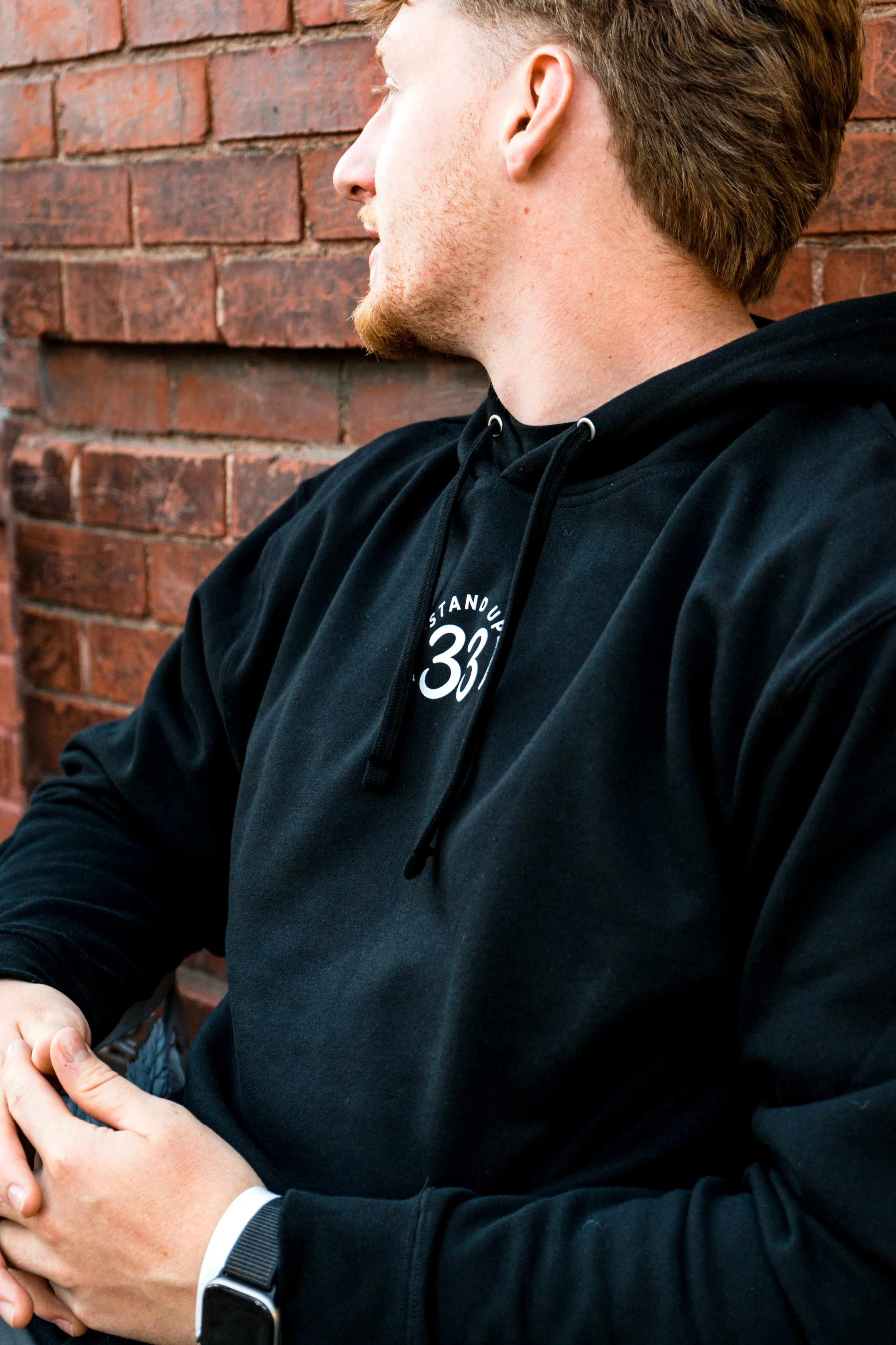 Person wearing a StandUp33 hoodie while sitting outdoors.