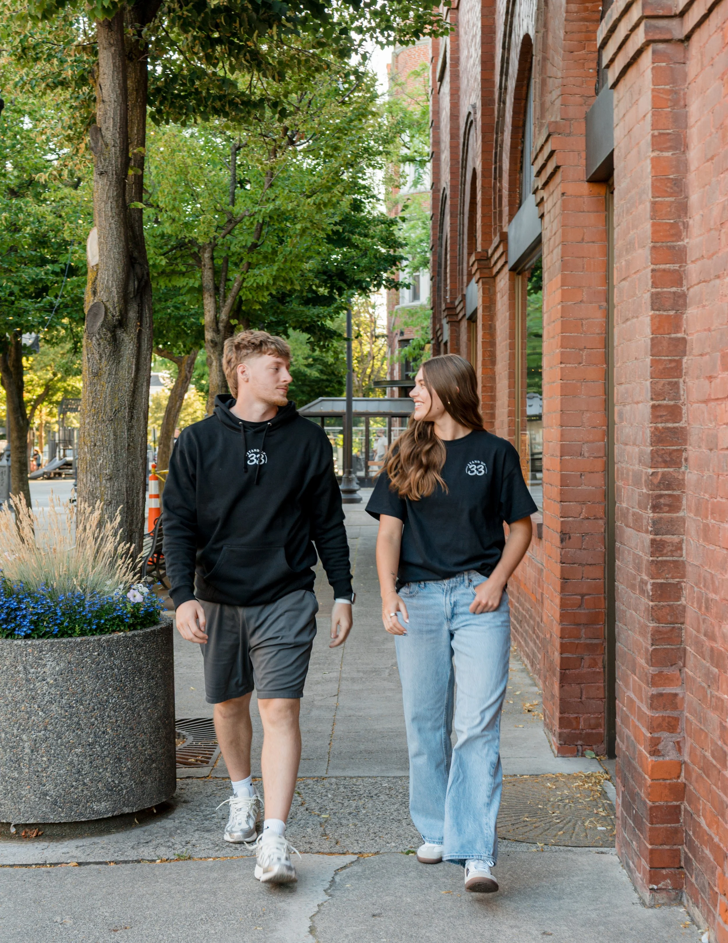 Two people wearing Standup33 apparel while walking and talking. 