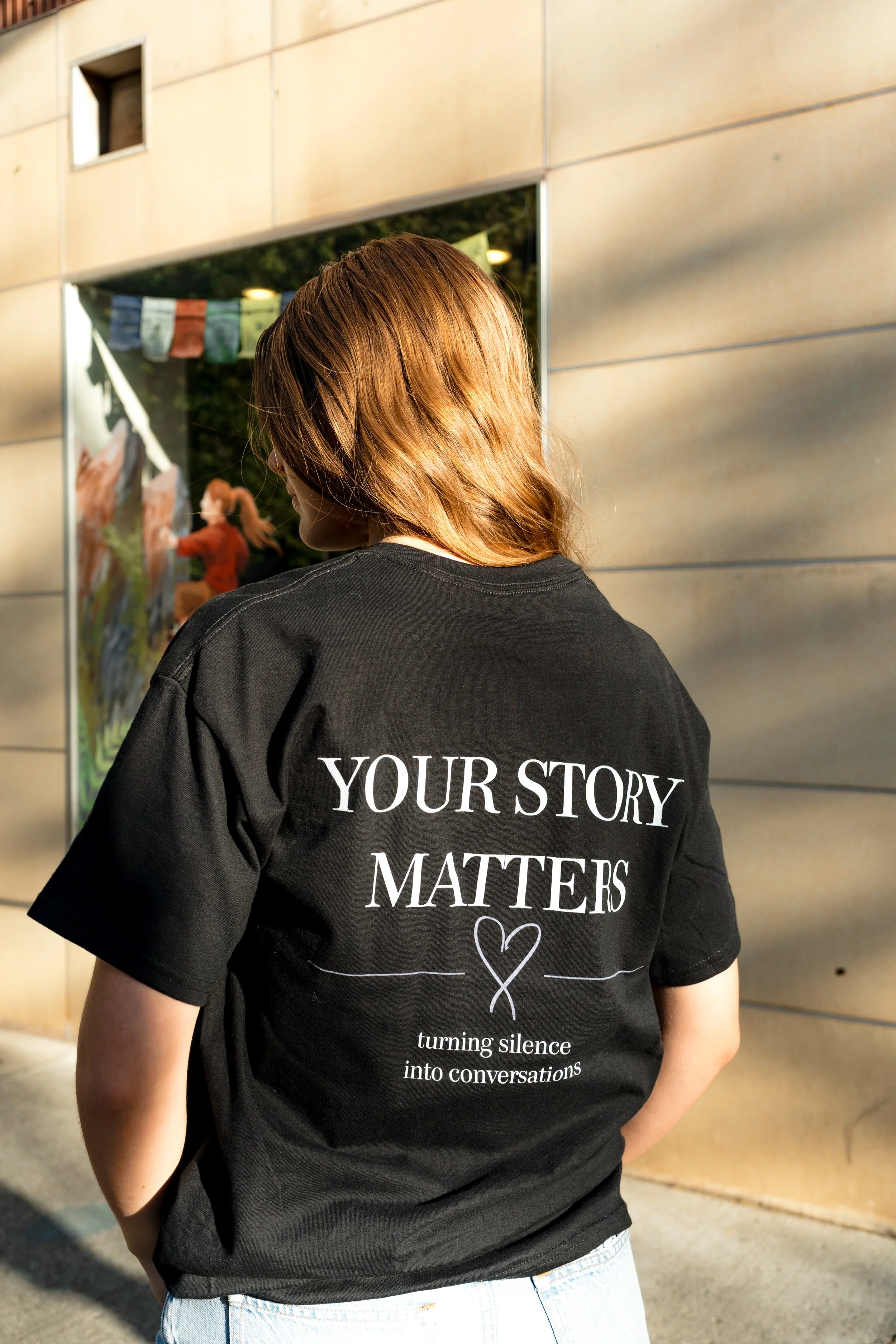 Back view of a person wearing a StandUp33 "Your Story Matters" T-shirt.