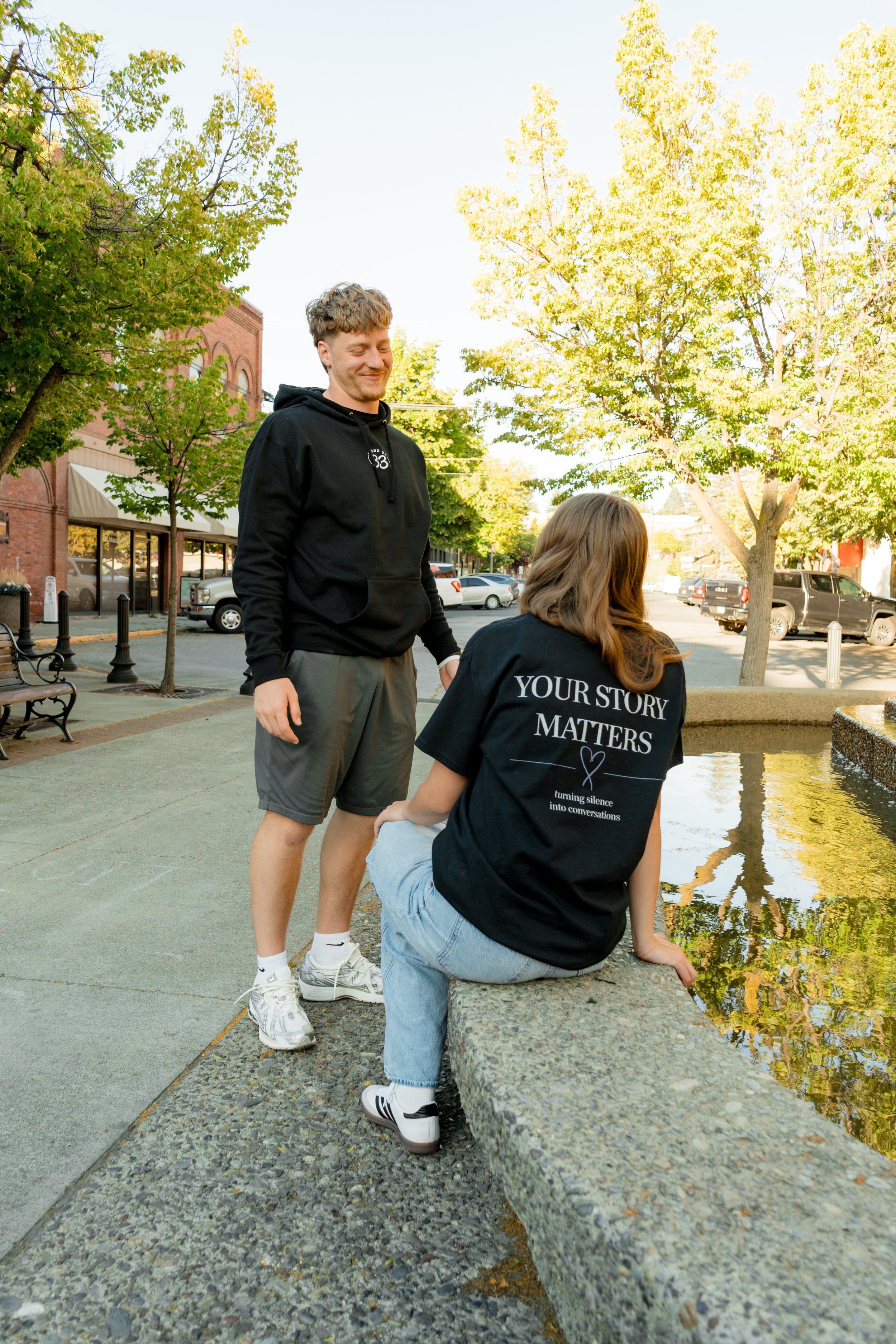Two people wearing StandUp33 awareness apparel while standing near a fountain.
