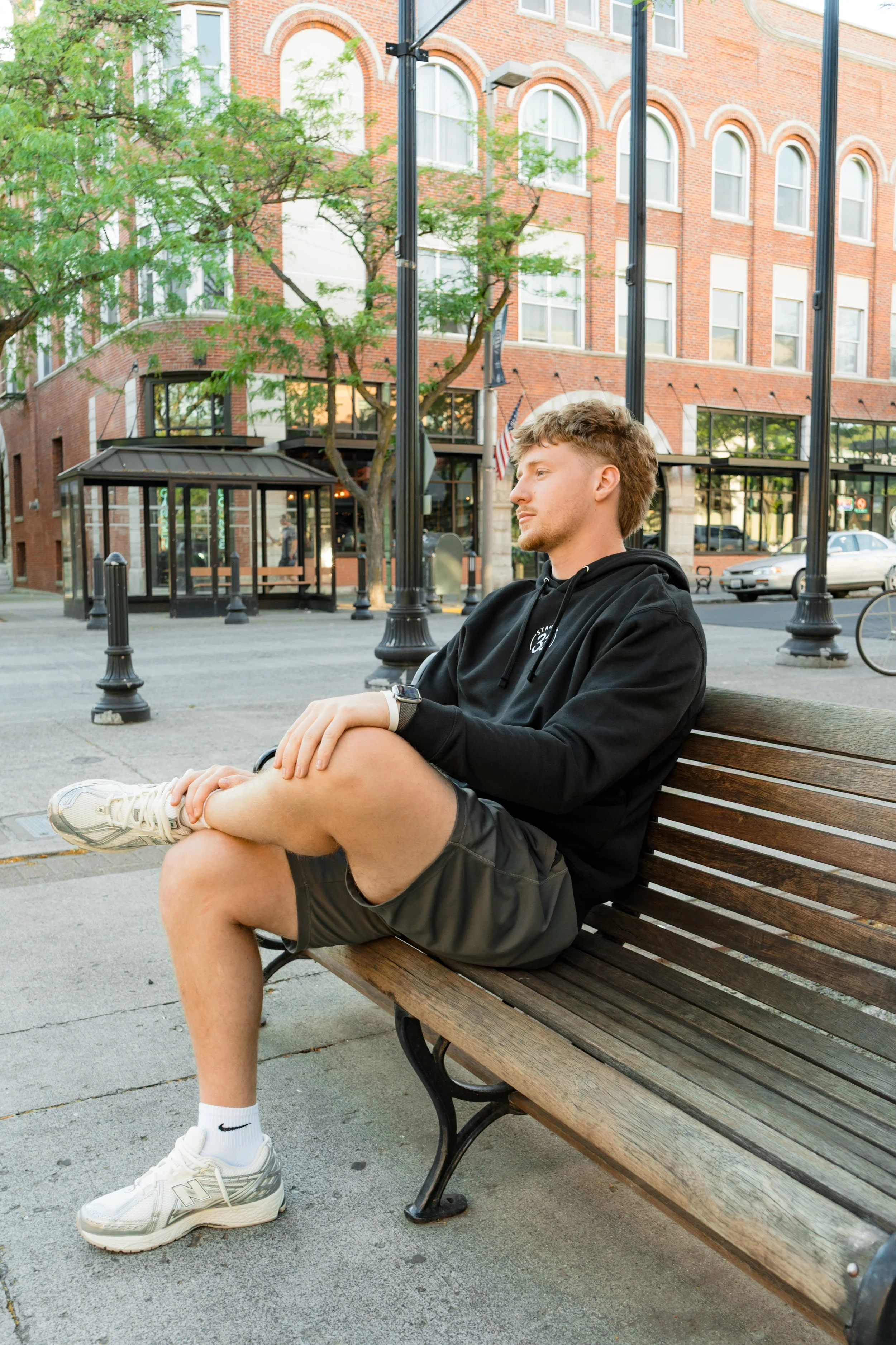 Person wearing a StandUp33 hoodie while sitting on a park bench.